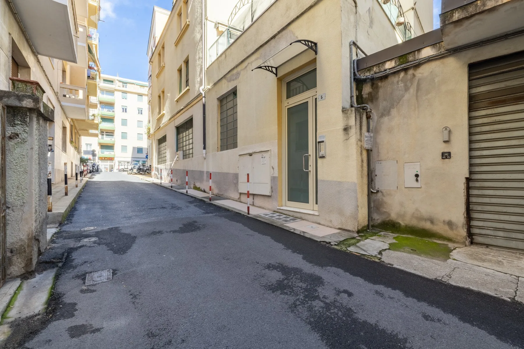 A narrow paved lane runs between closely spaced buildings.