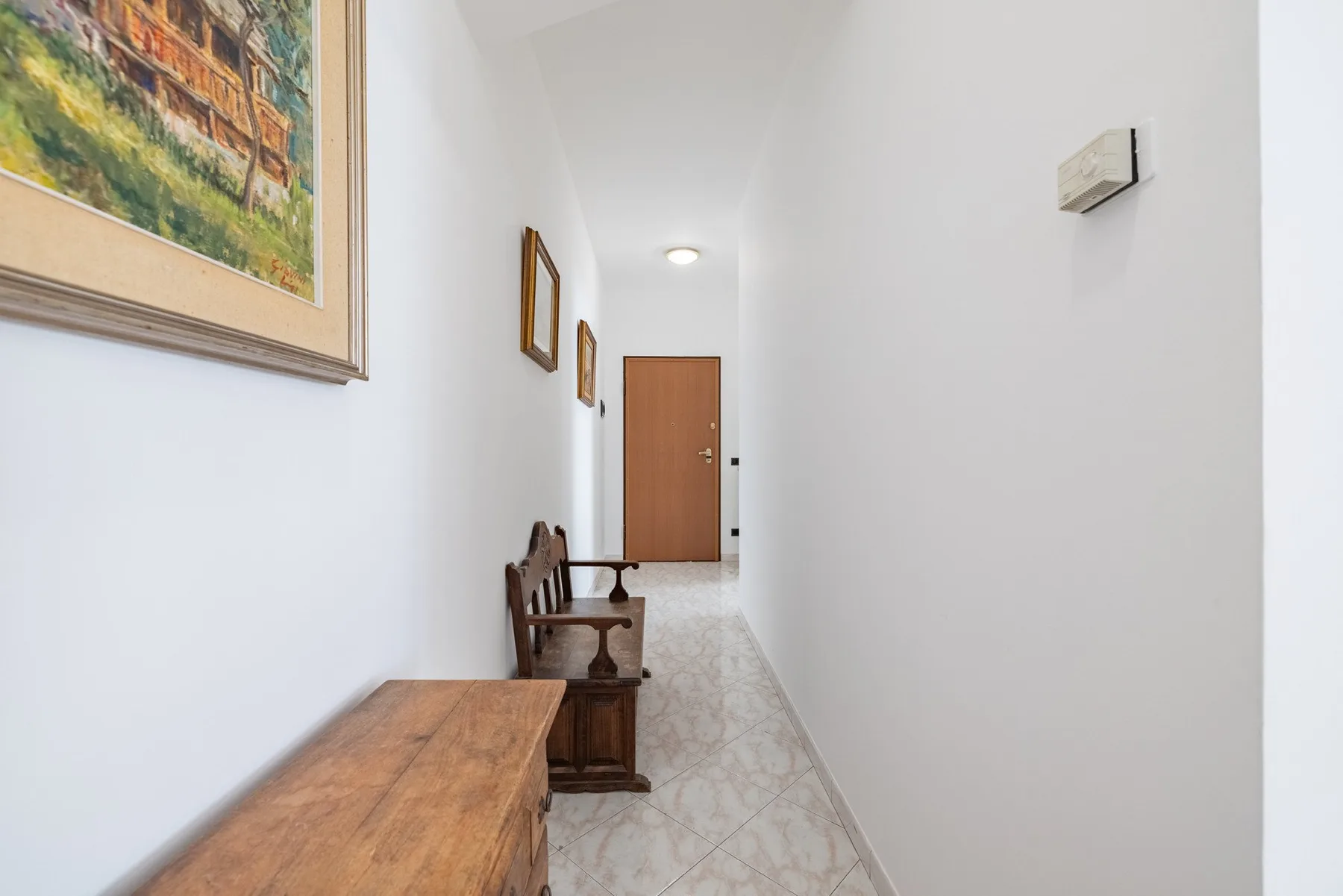 A bright hallway with wooden furniture and a closed door at the far end.