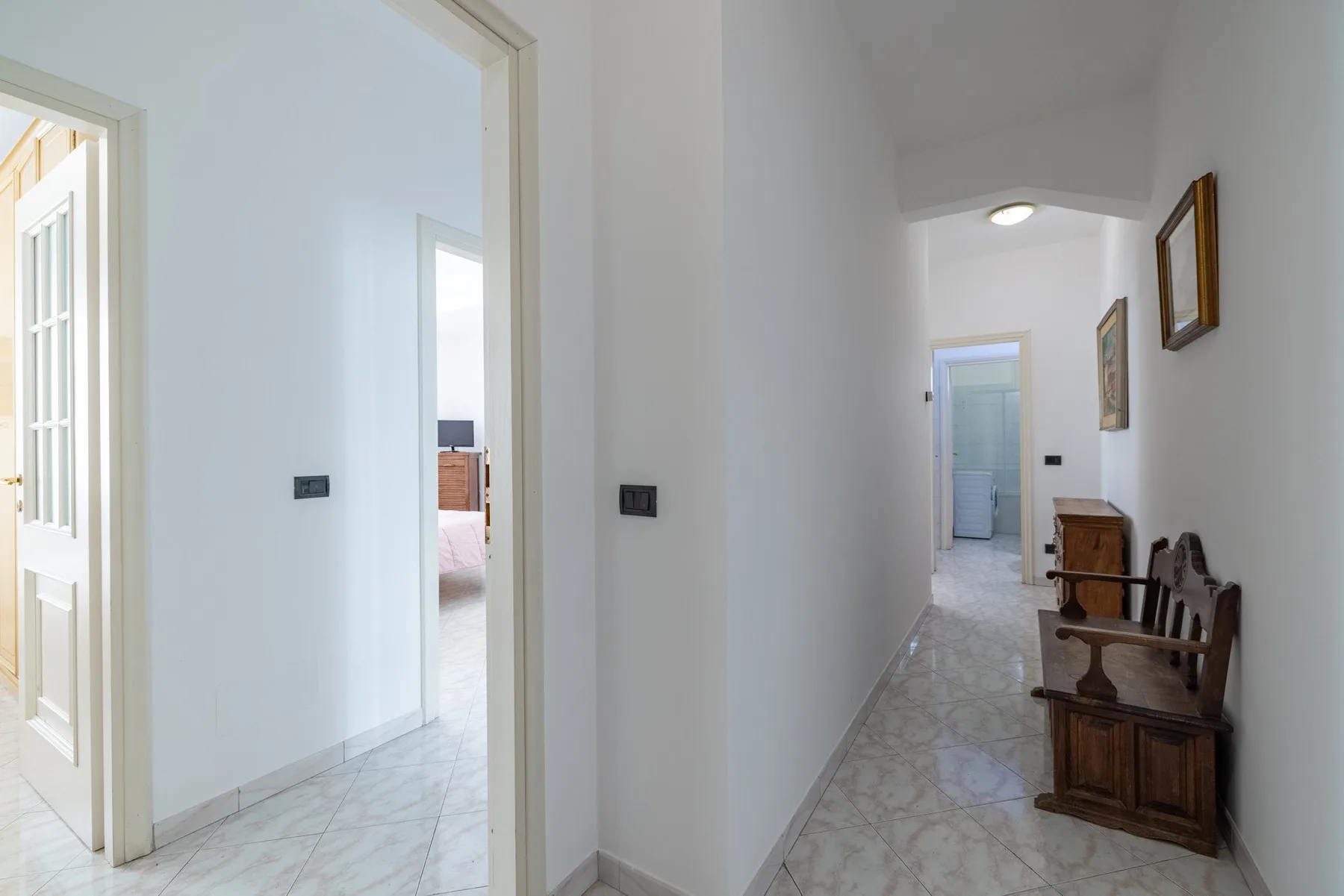 A bright hallway with tiled flooring and several doorways.