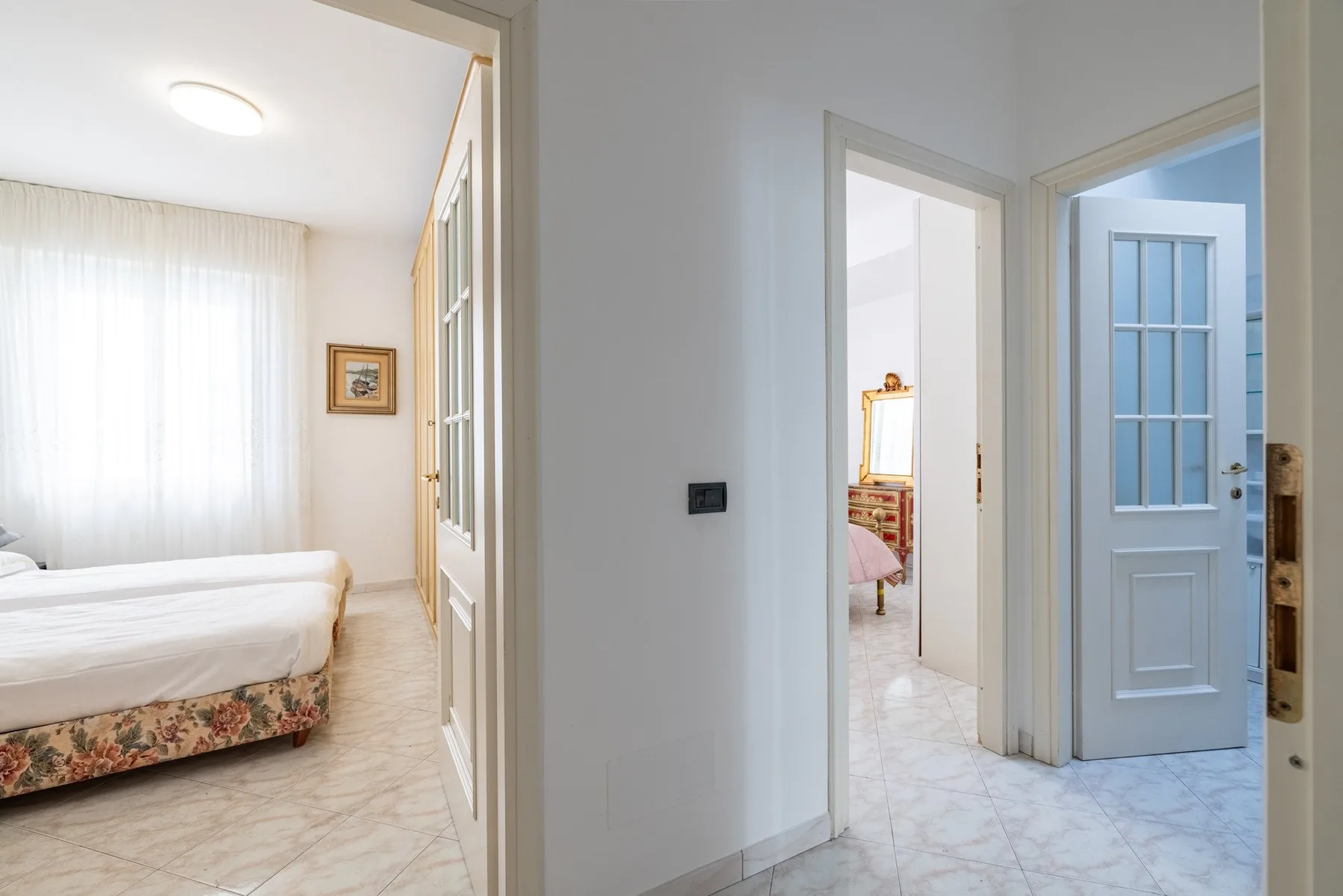 A bright bedroom opens onto a hallway with a blue door.