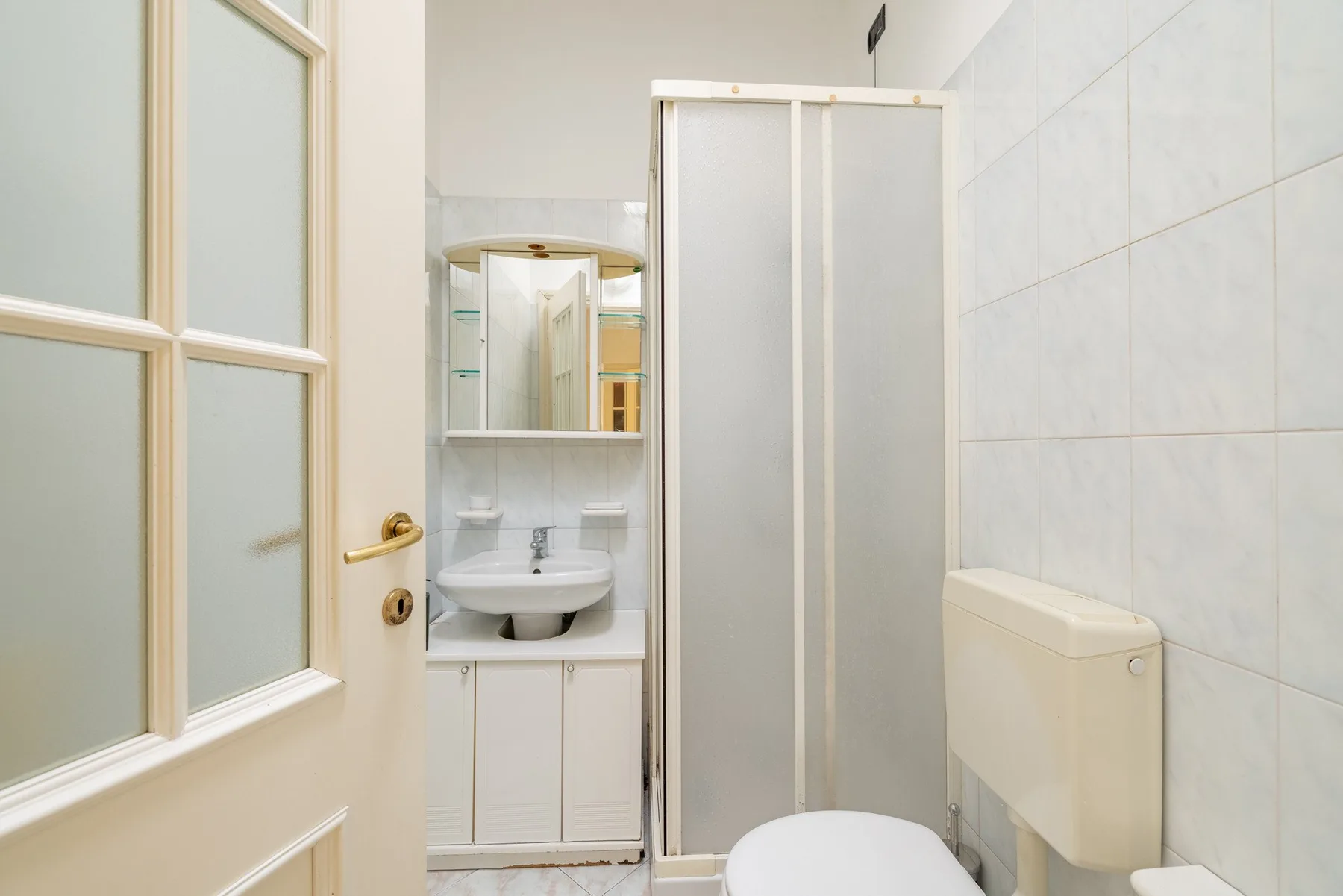 A tiled bathroom with a shower, sink, and mirror.