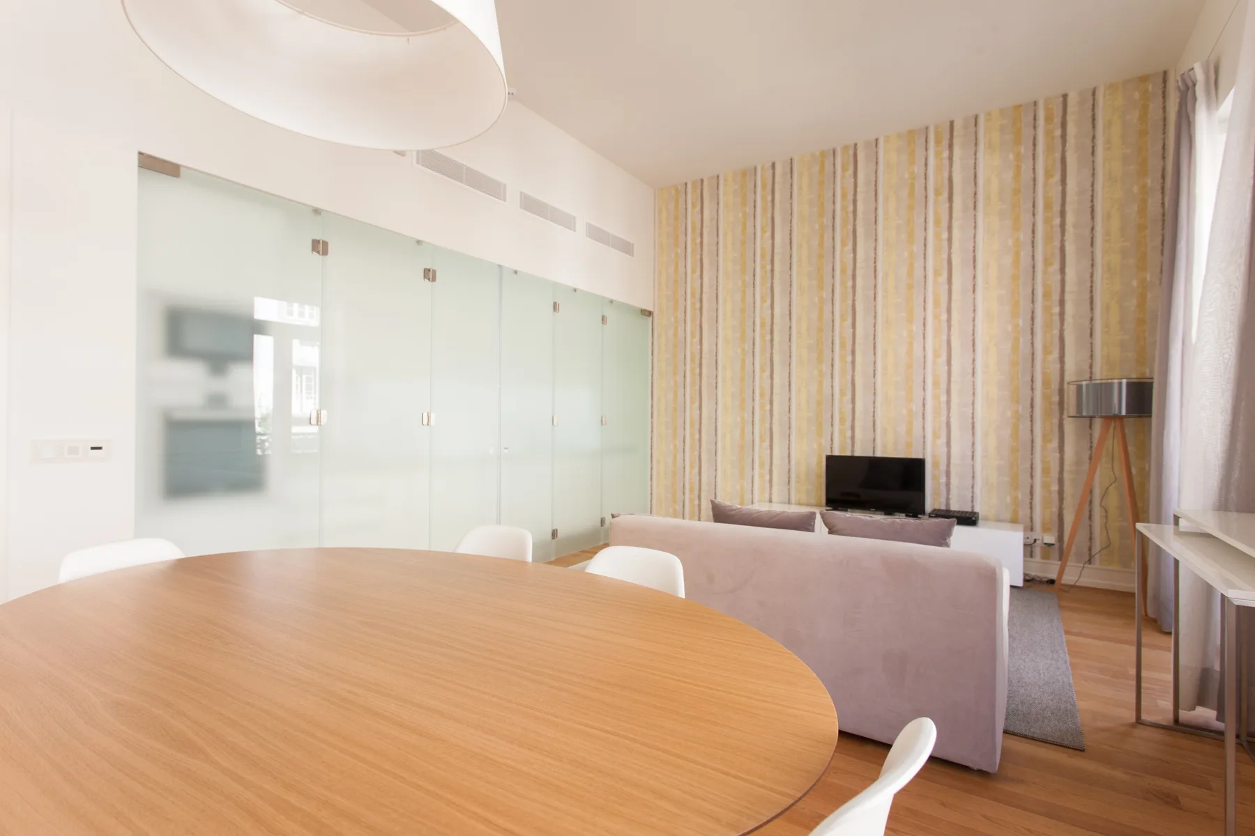 A bright living and dining area with a round table and seating.