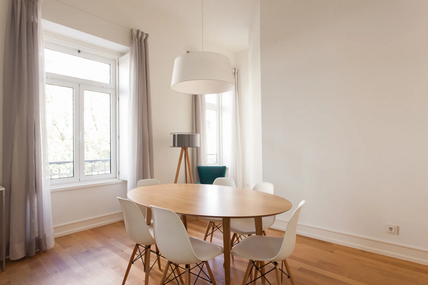 A dining area with a wooden table and chairs beside a large window.