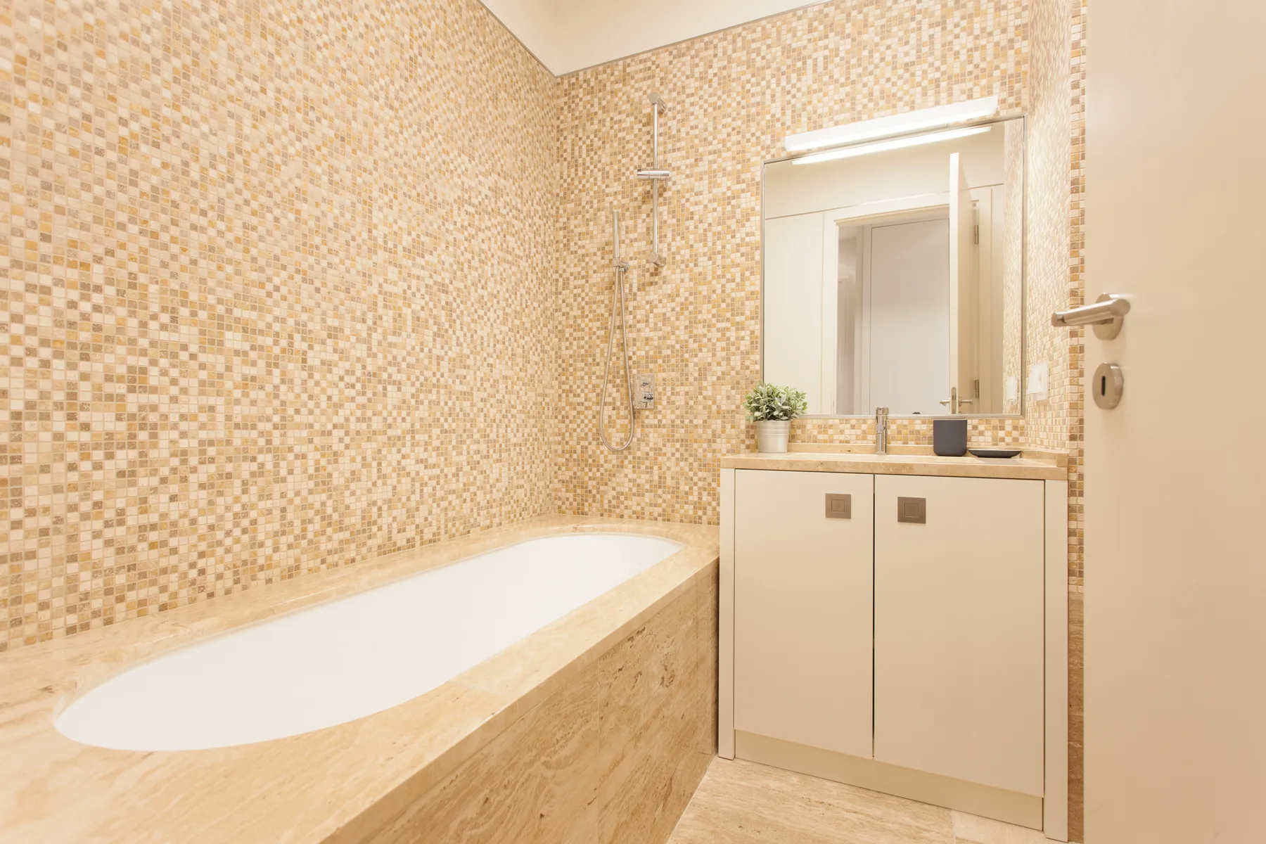 A bathroom with a built-in bathtub and a sink beneath a mirror.