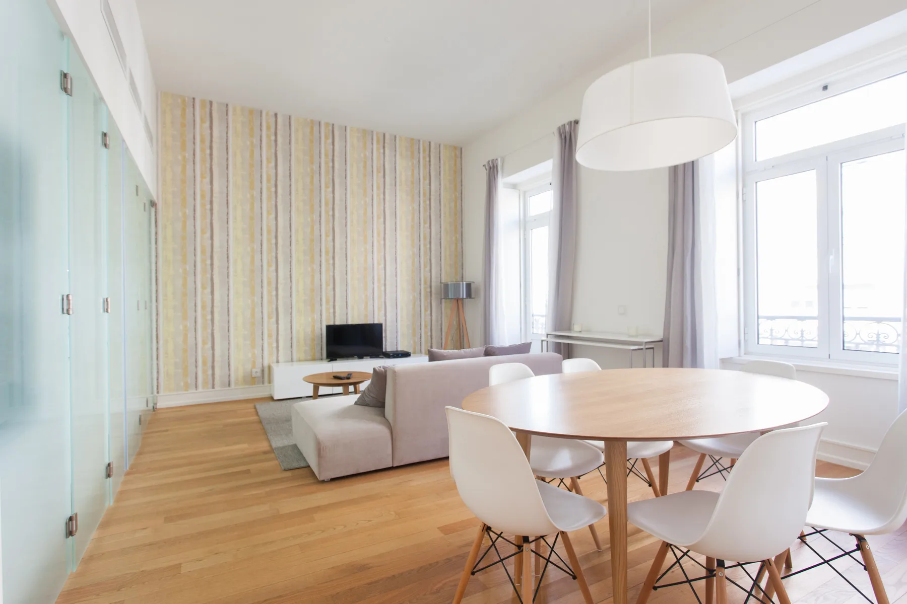 A bright living and dining area with a round table beside large windows.