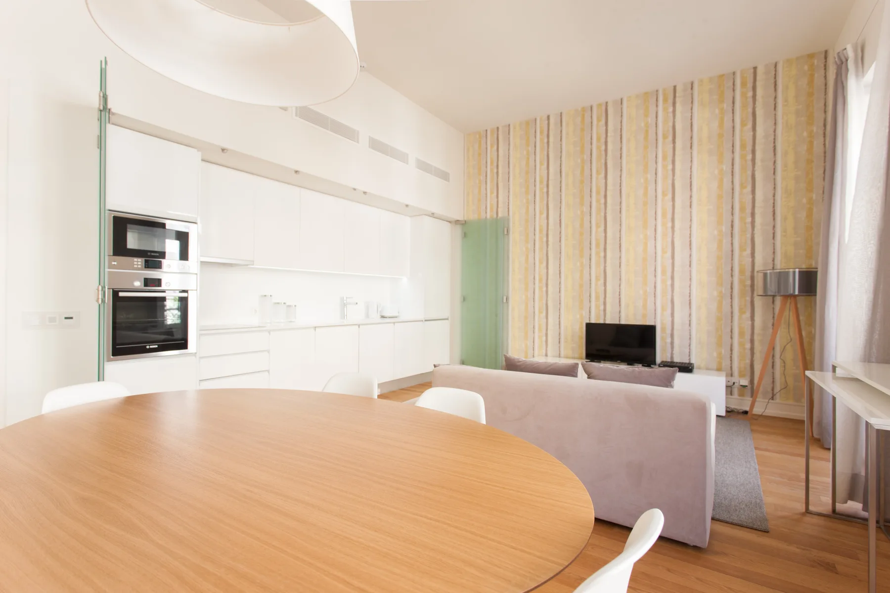 An open-plan living area with a dining table, kitchen, and seating.