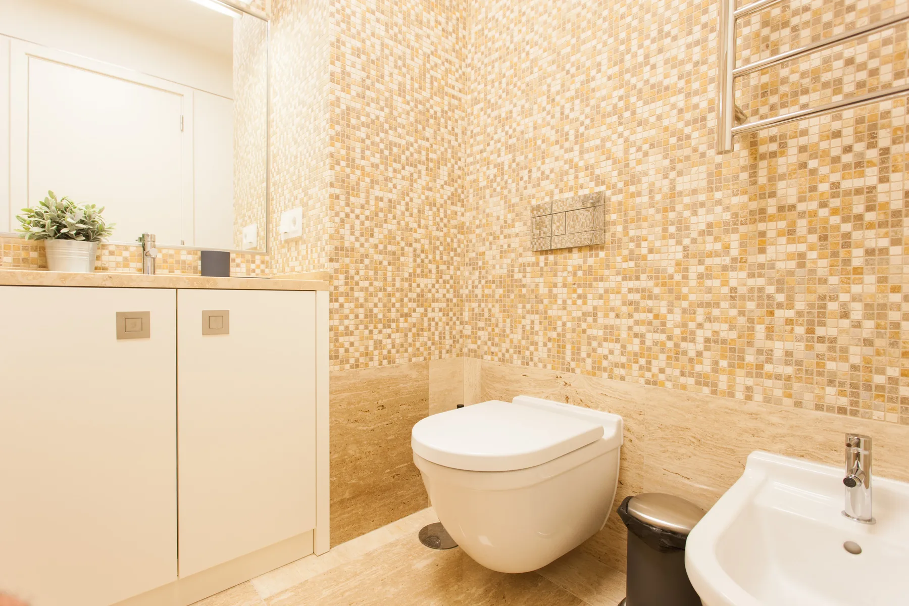 A tiled bathroom with a wall-mounted toilet and sink.