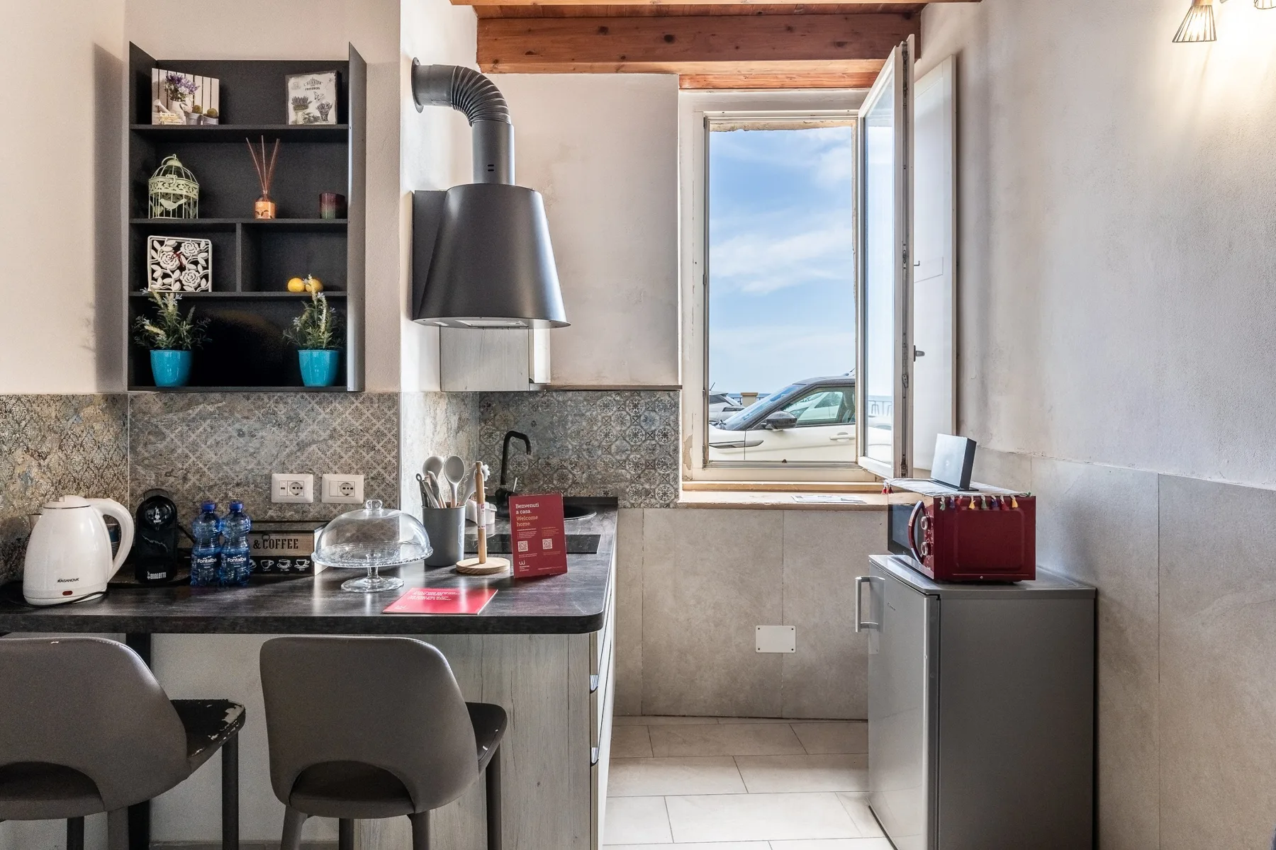 Una cocina compacta con barra, asientos y una ventana con vista a la calle.