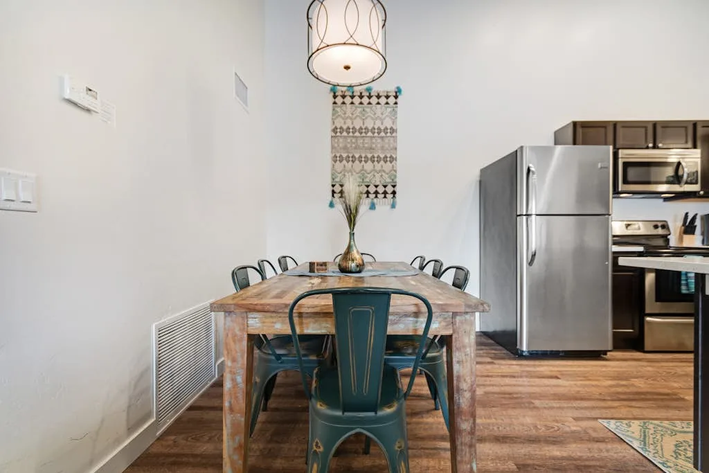 Comedor con una mesa de madera y sillas junto a la cocina.