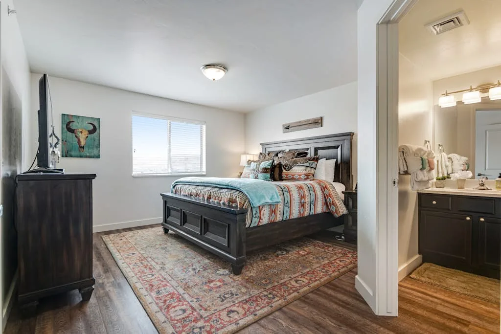 Un dormitorio con una cama grande, ropa de cama estampada y una alfombra.