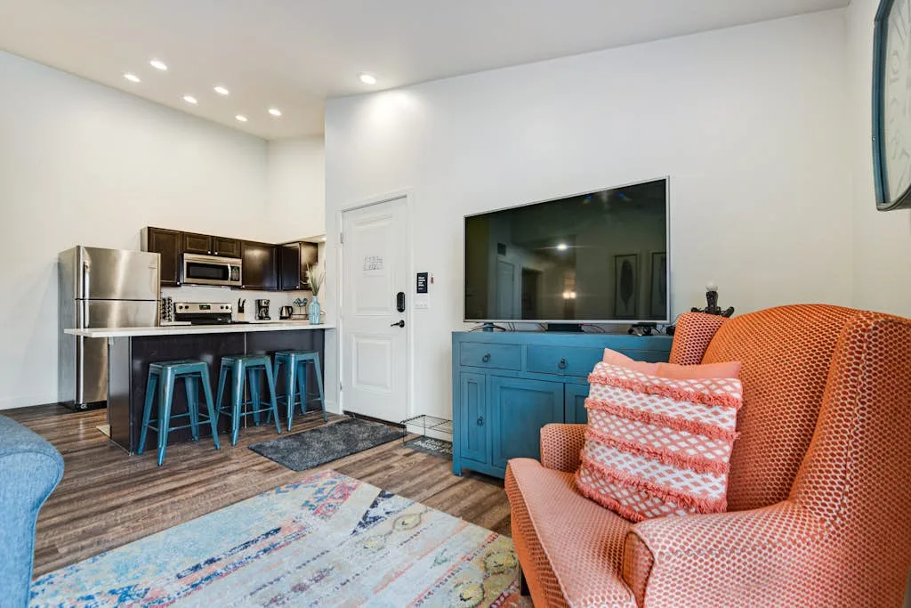 Una sala de estar de concepto abierto con televisor, asientos y una barra de cocina.