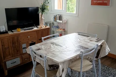 A dining area with a table, chairs, and a television on a wooden cabinet.