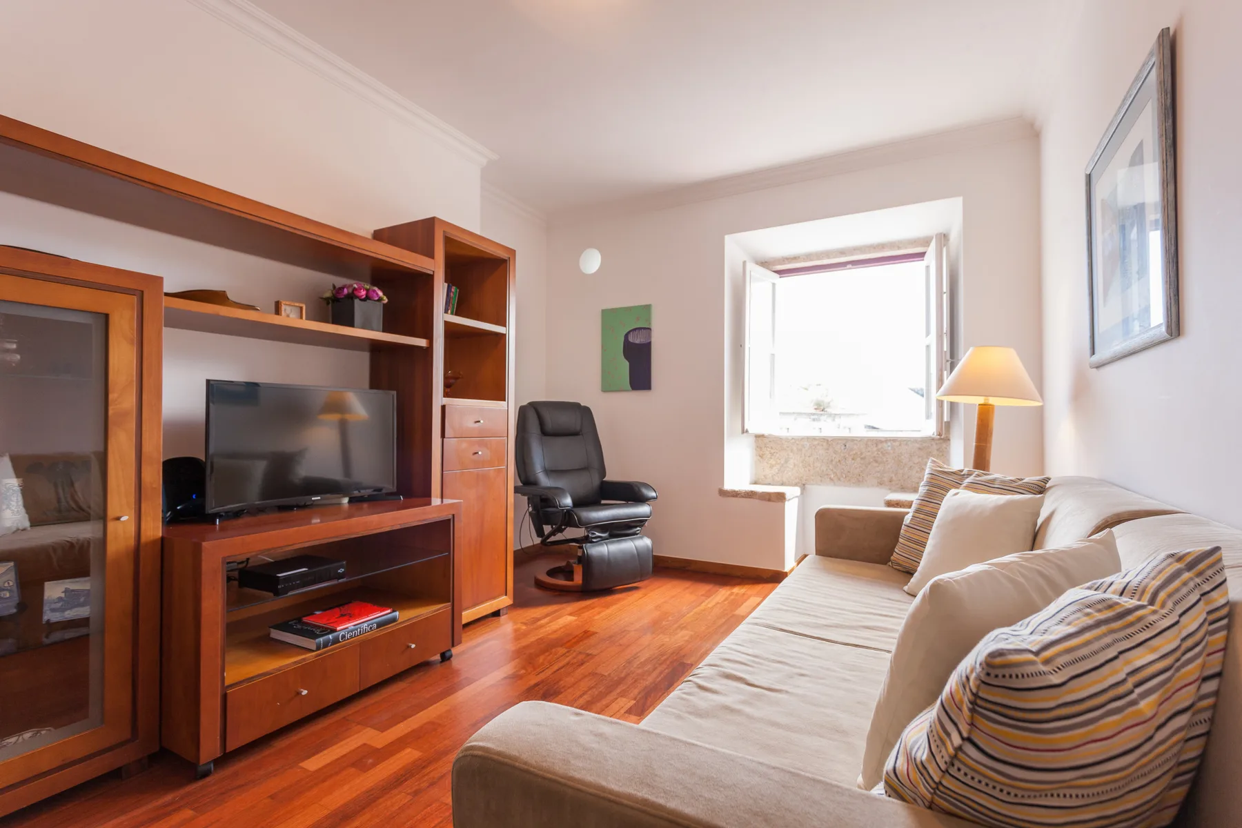 Una sala de estar con televisión, asientos y una ventana.