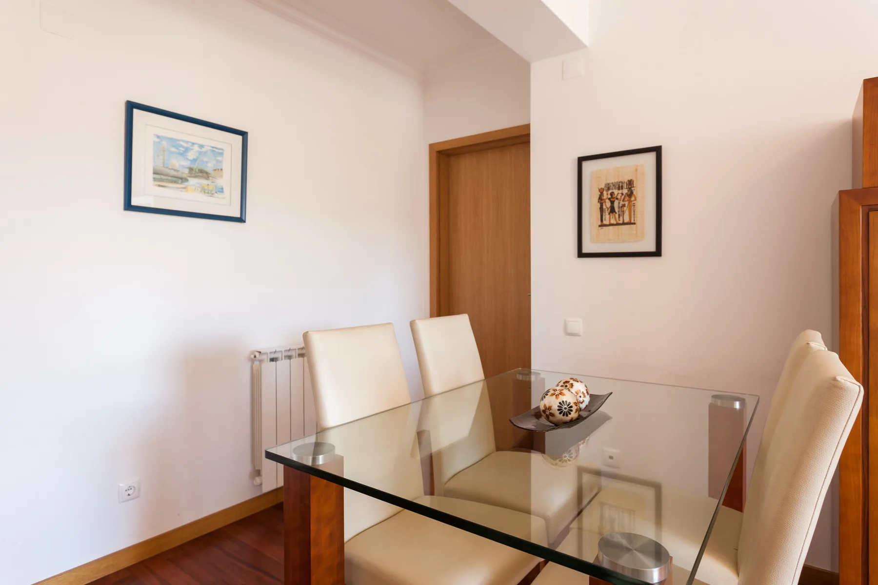 Comedor con una mesa de vidrio y asientos tapizados.