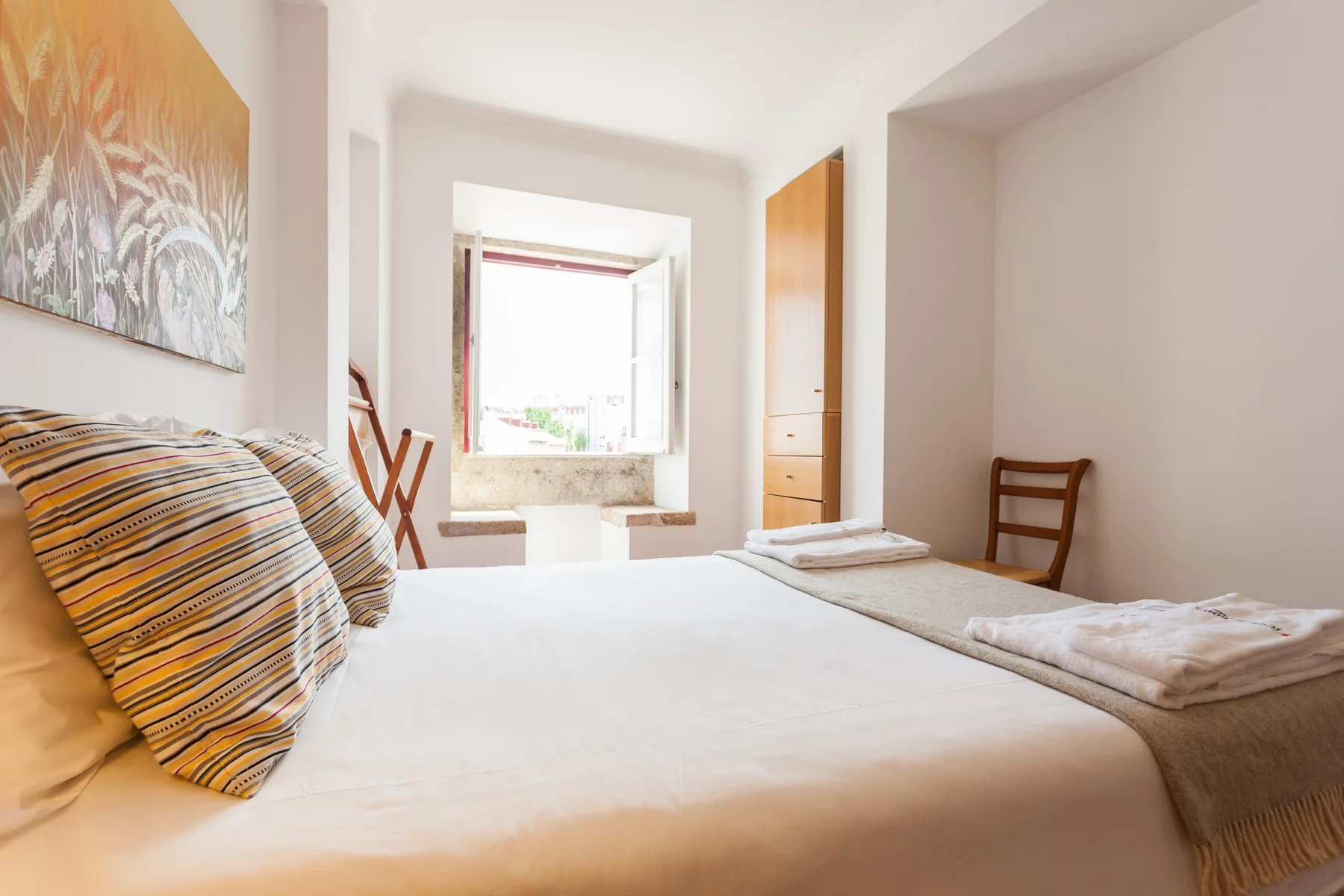 Un dormitorio luminoso con una cama grande y una ventana al fondo.