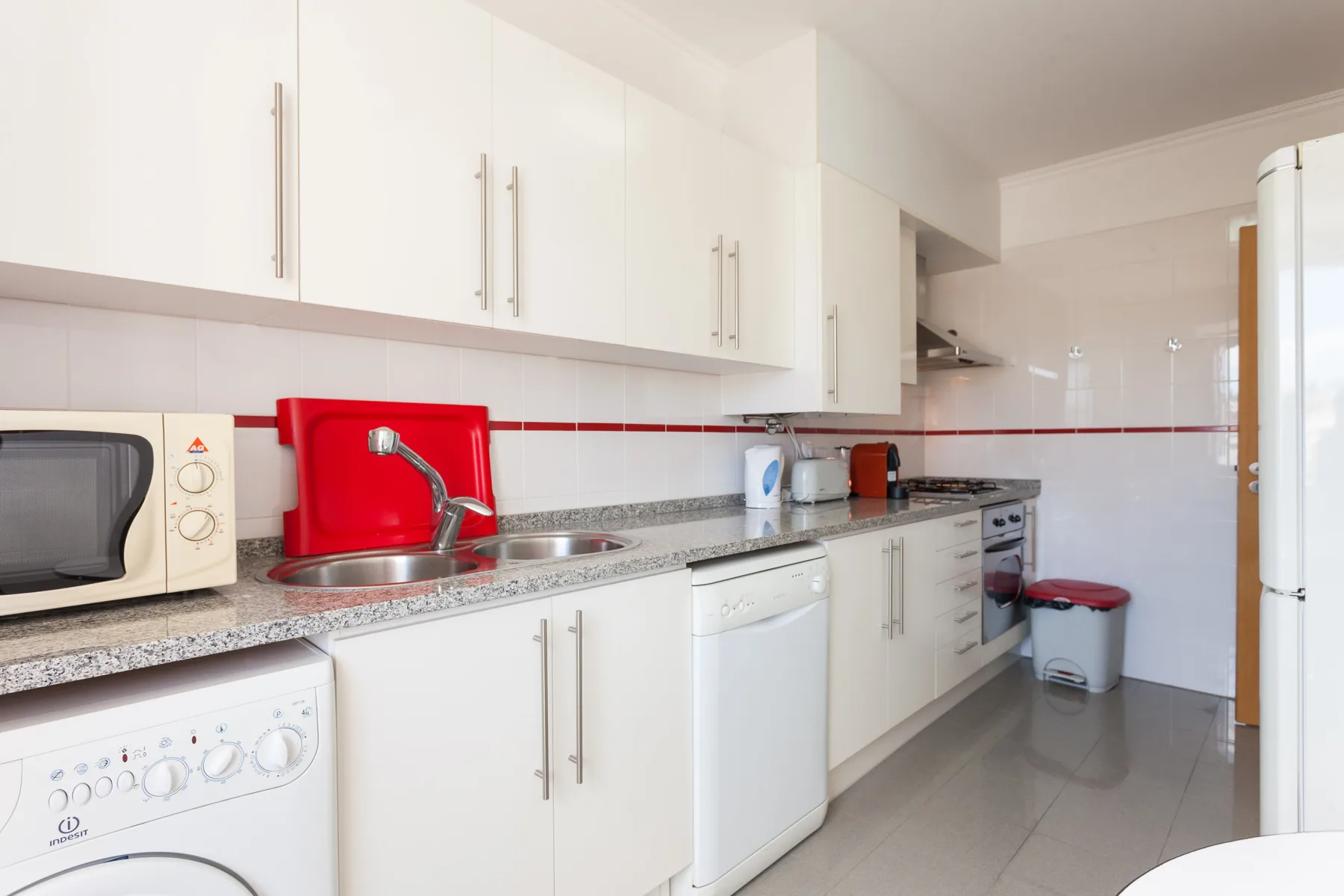 Una cocina luminosa con gabinetes blancos y una encimera larga.