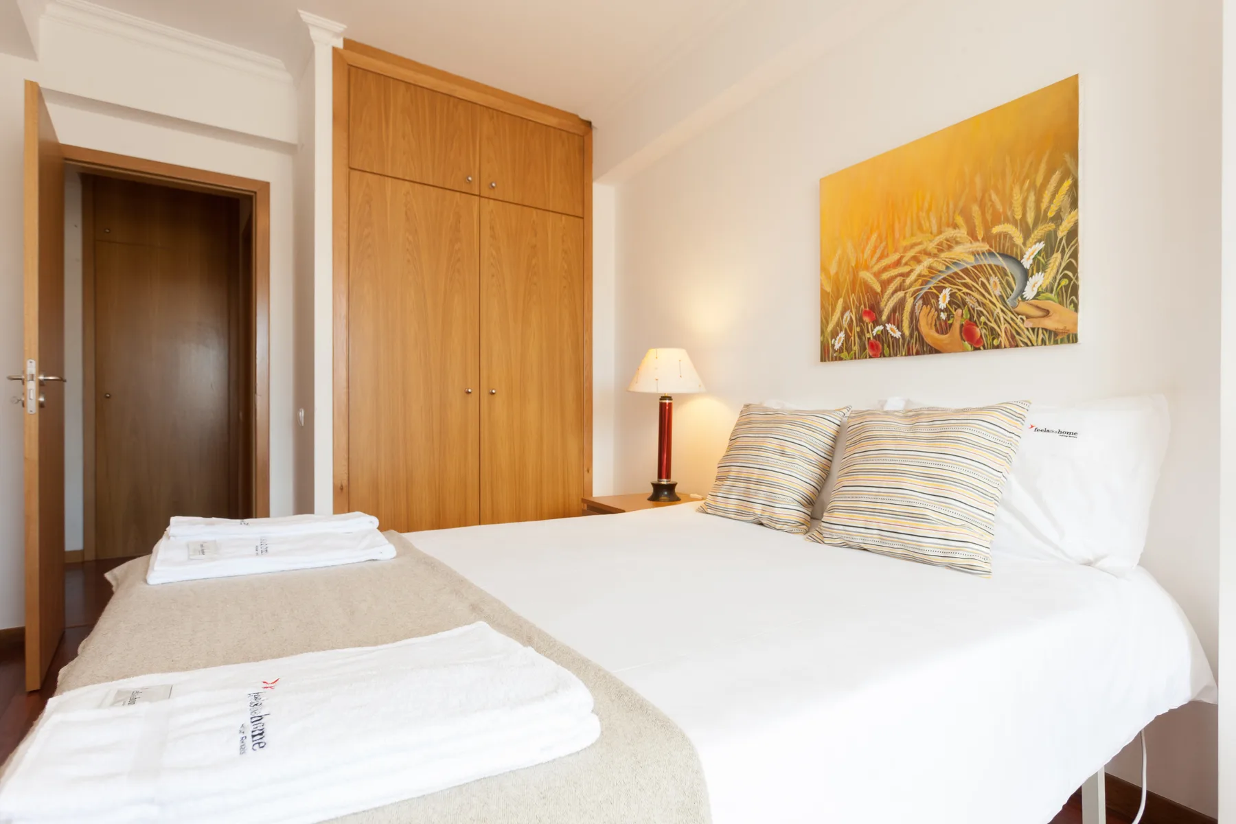 Dormitorio con una cama, almohadas a rayas y un armario de madera.