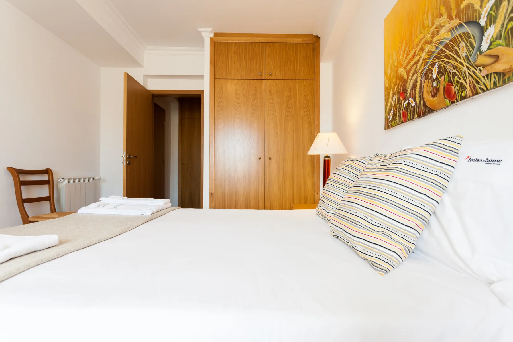 Un dormitorio con una cama bien hecha y un armario de madera.