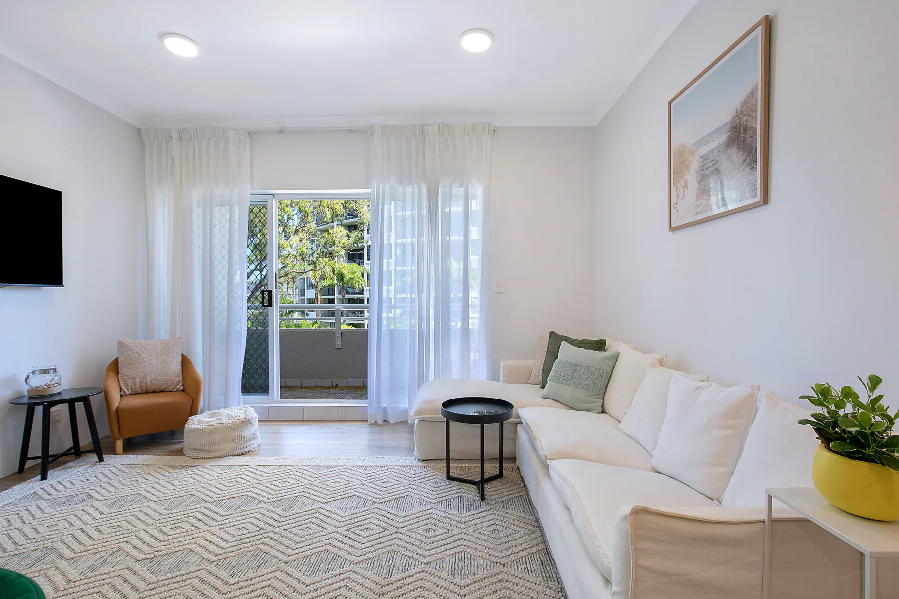 Una sala de estar luminosa con asientos color crema y puertas corredizas de vidrio.