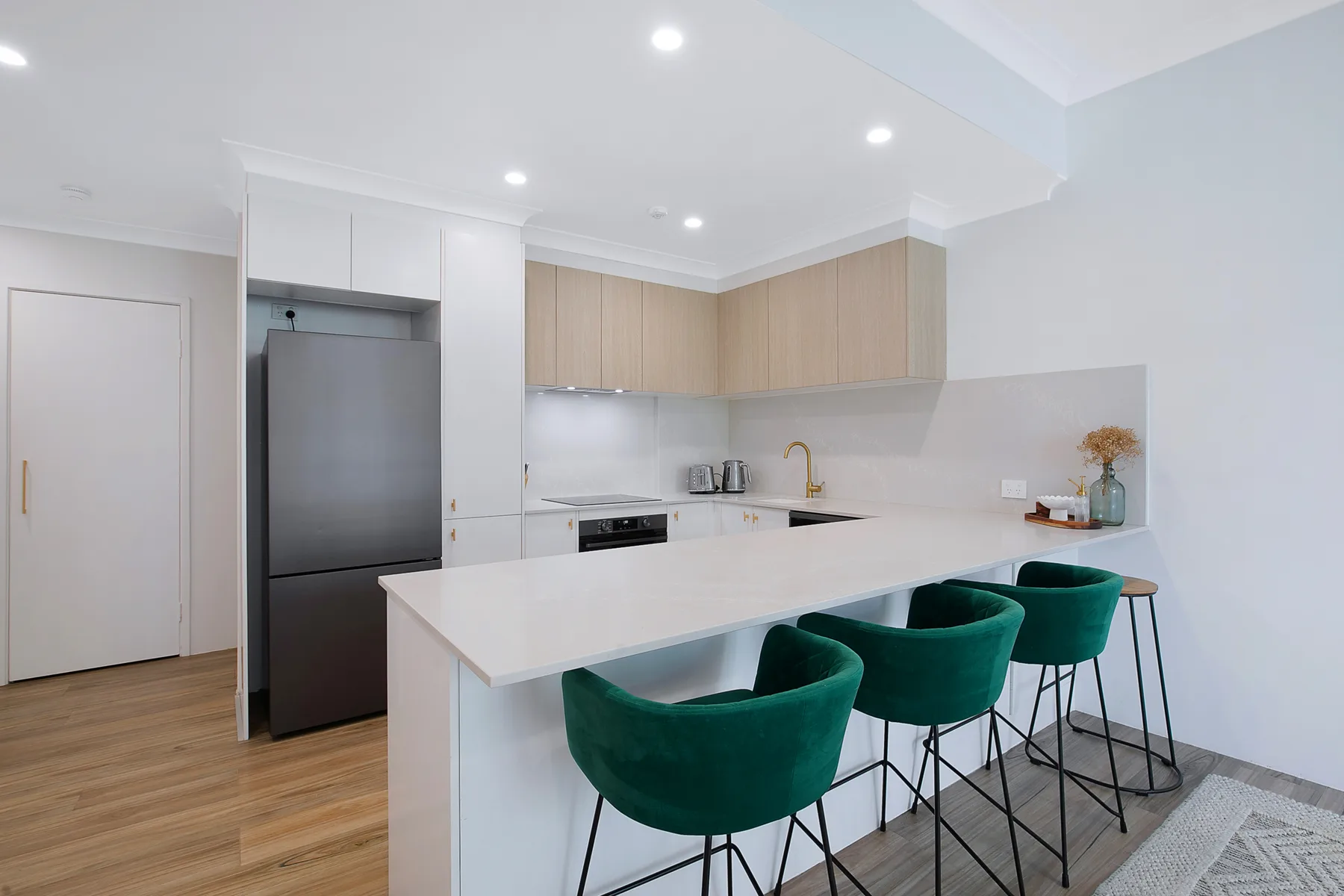Una cocina moderna y luminosa con una isla blanca y taburetes verdes.