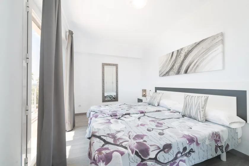 A bright bedroom with a floral bedspread and abstract wall art.