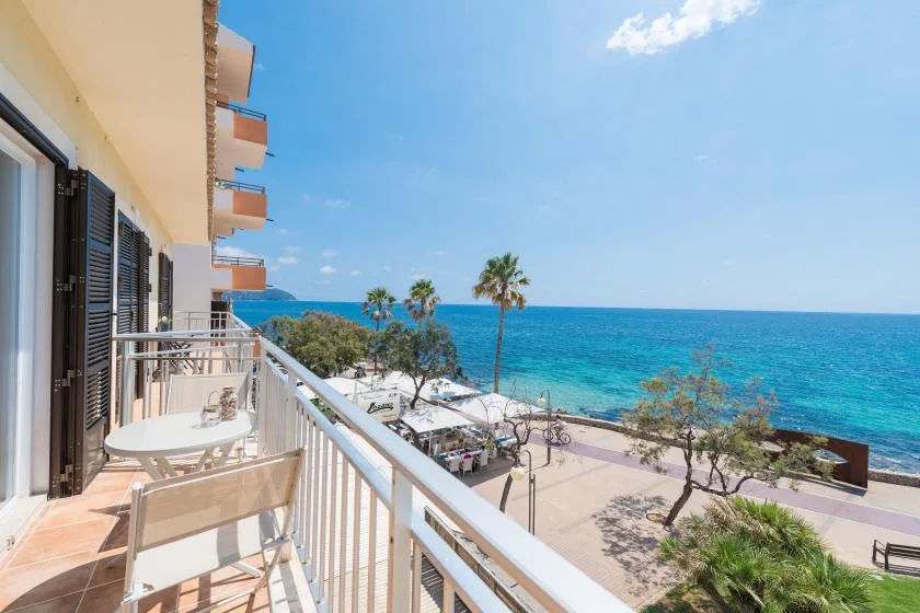 A balcony overlooks the beach and blue sea under a clear sky.