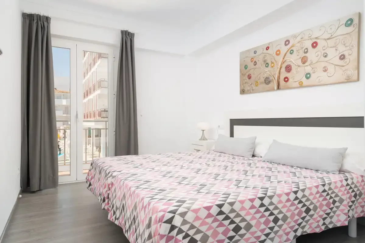 A bedroom with a large bed and glass doors opening onto a balcony.