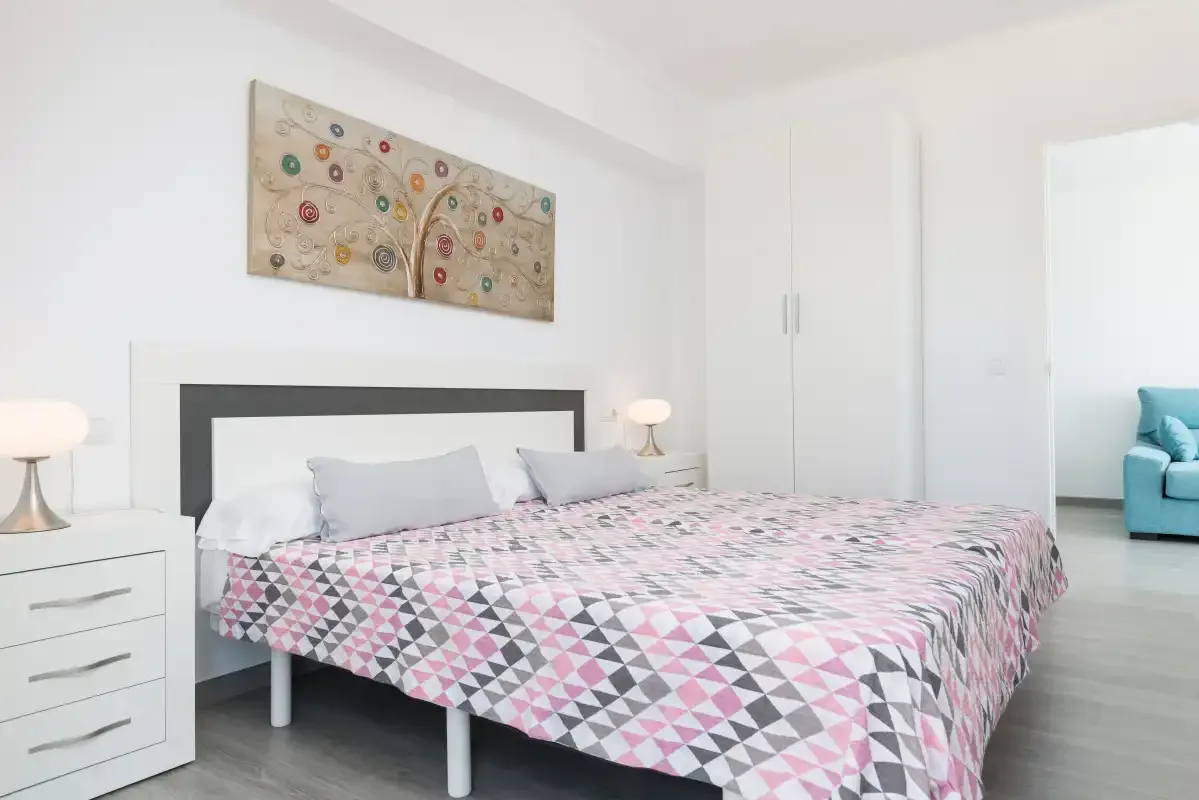 A bedroom with a double bed covered in a geometric patterned bedspread.