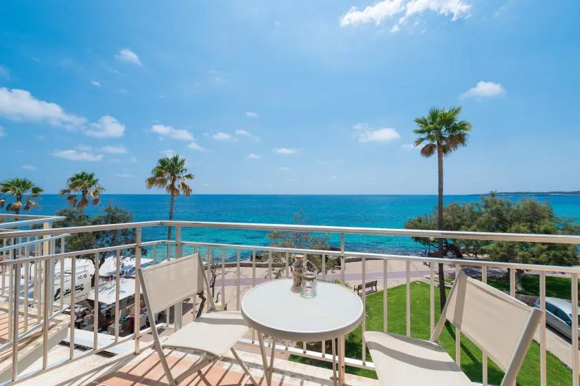A balcony dining area overlooks the sea, with a round table and outdoor seating.