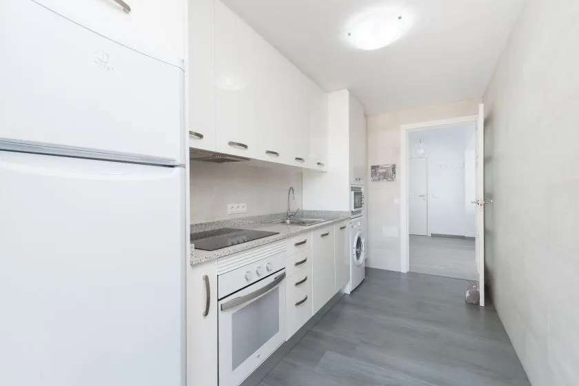 A bright kitchen with white cabinets, a countertop, and built-in appliances.