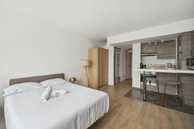 A bedroom with a bed and an open kitchen area.