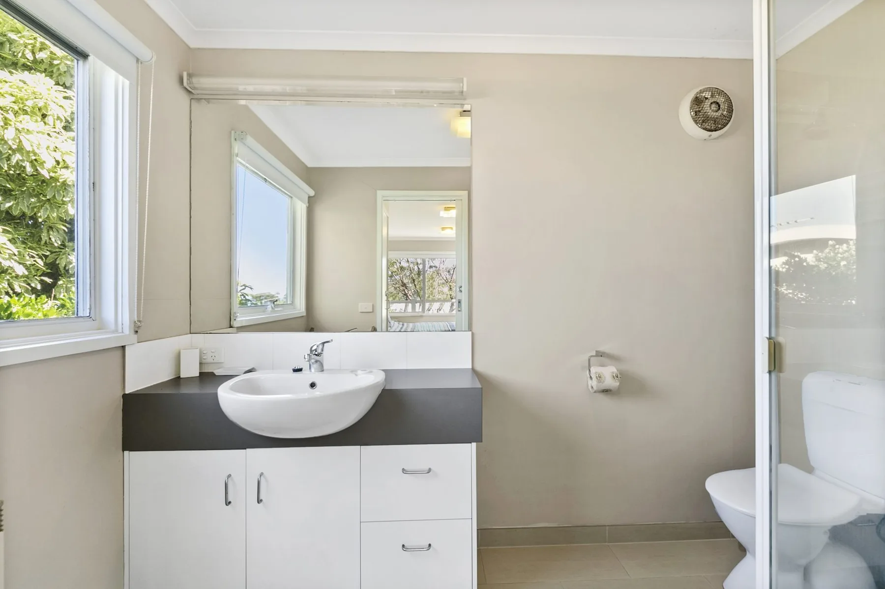 A bathroom vanity with a sink sits beside a glass shower.
