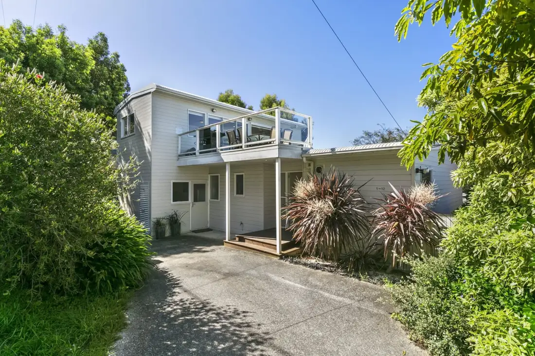 A two-story house with an upper balcony and a paved driveway.