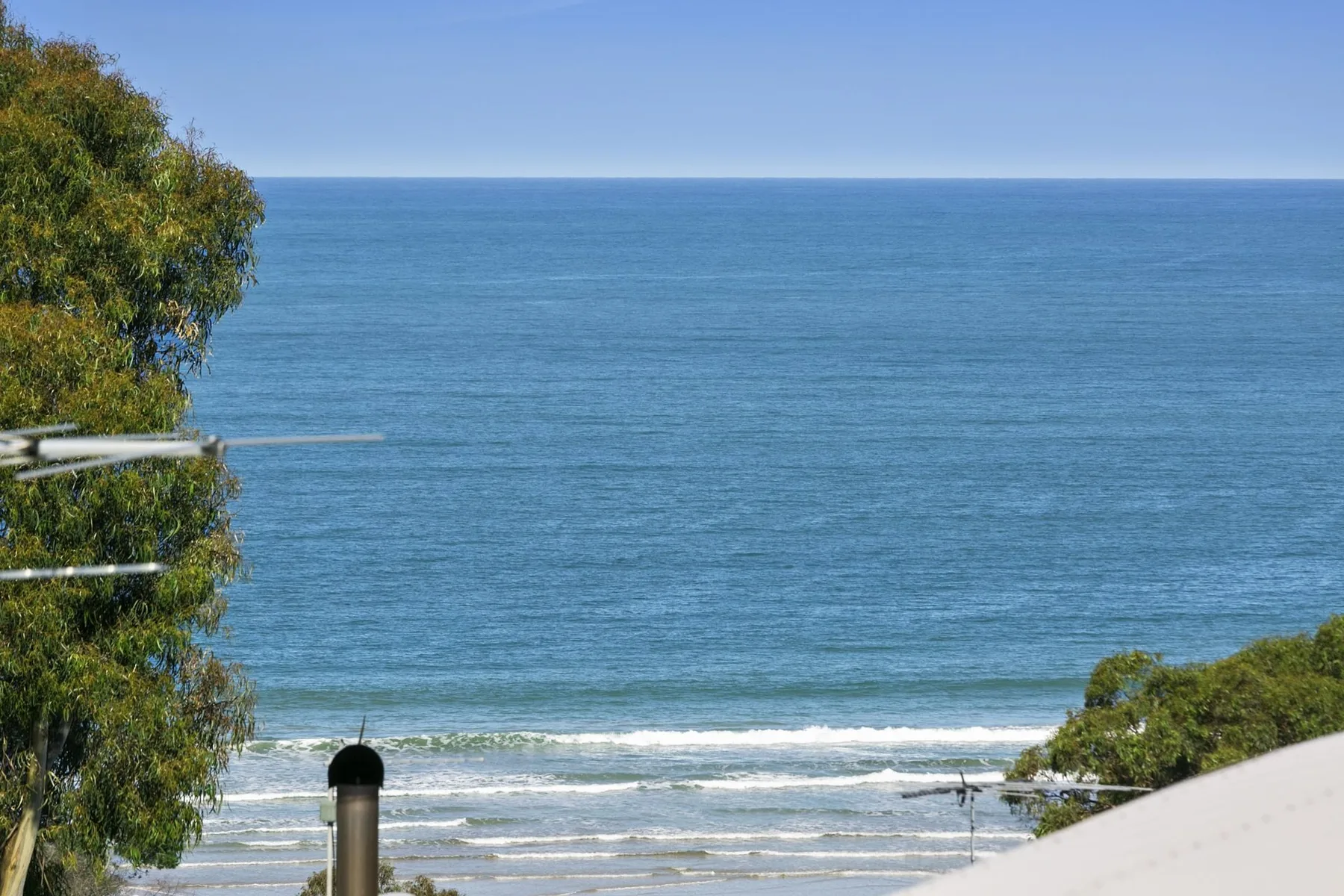 Ocean view with waves reaching the shoreline beneath a clear sky.
