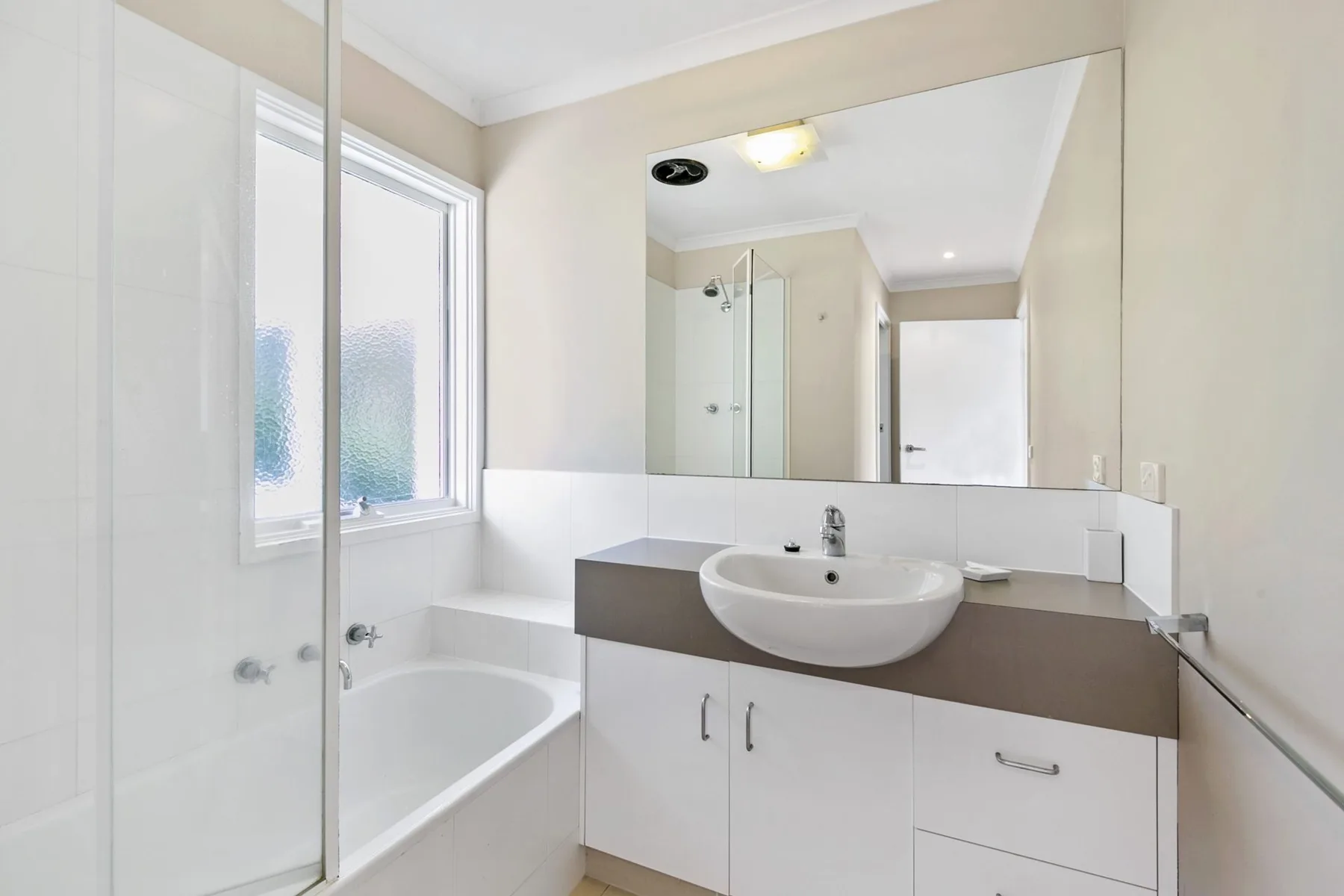 Bathroom with a bathtub, shower, and sink beneath a large mirror.