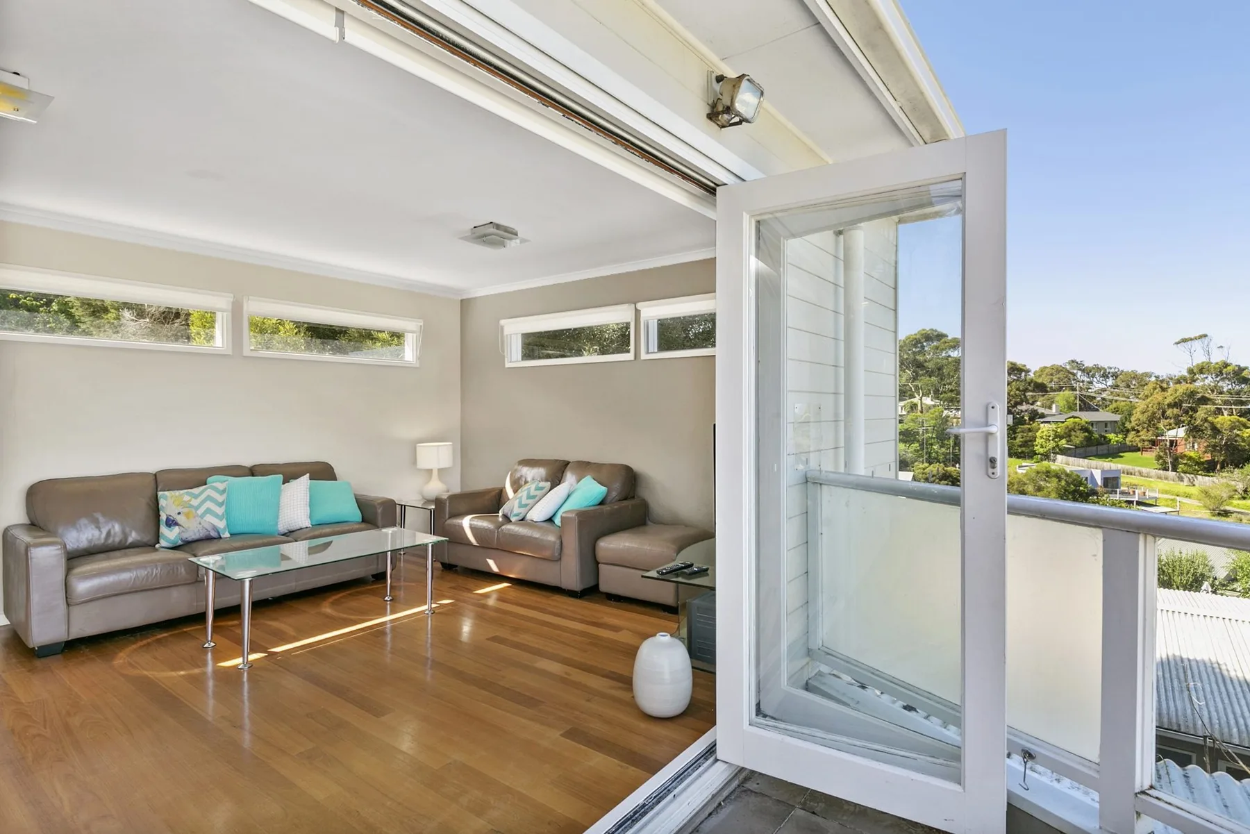 A bright living room with seating, a coffee table, and an open glass door.