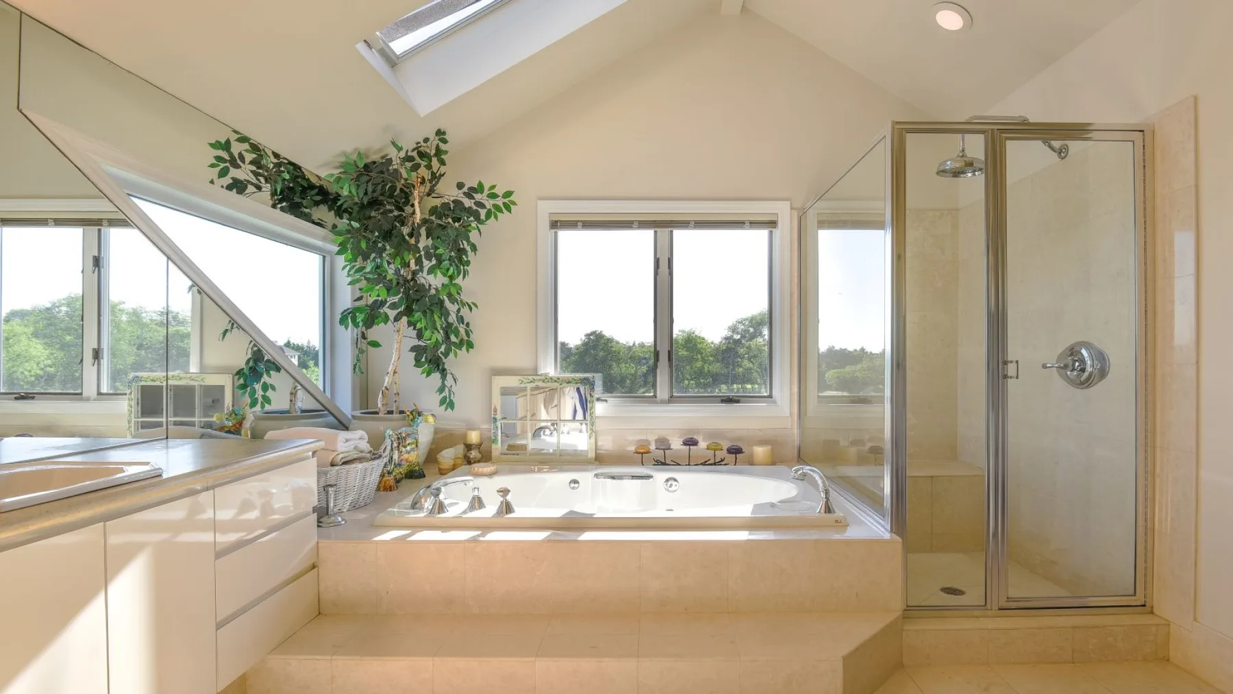 Un baño luminoso con una bañera grande, ventanas y una ducha de vidrio.
