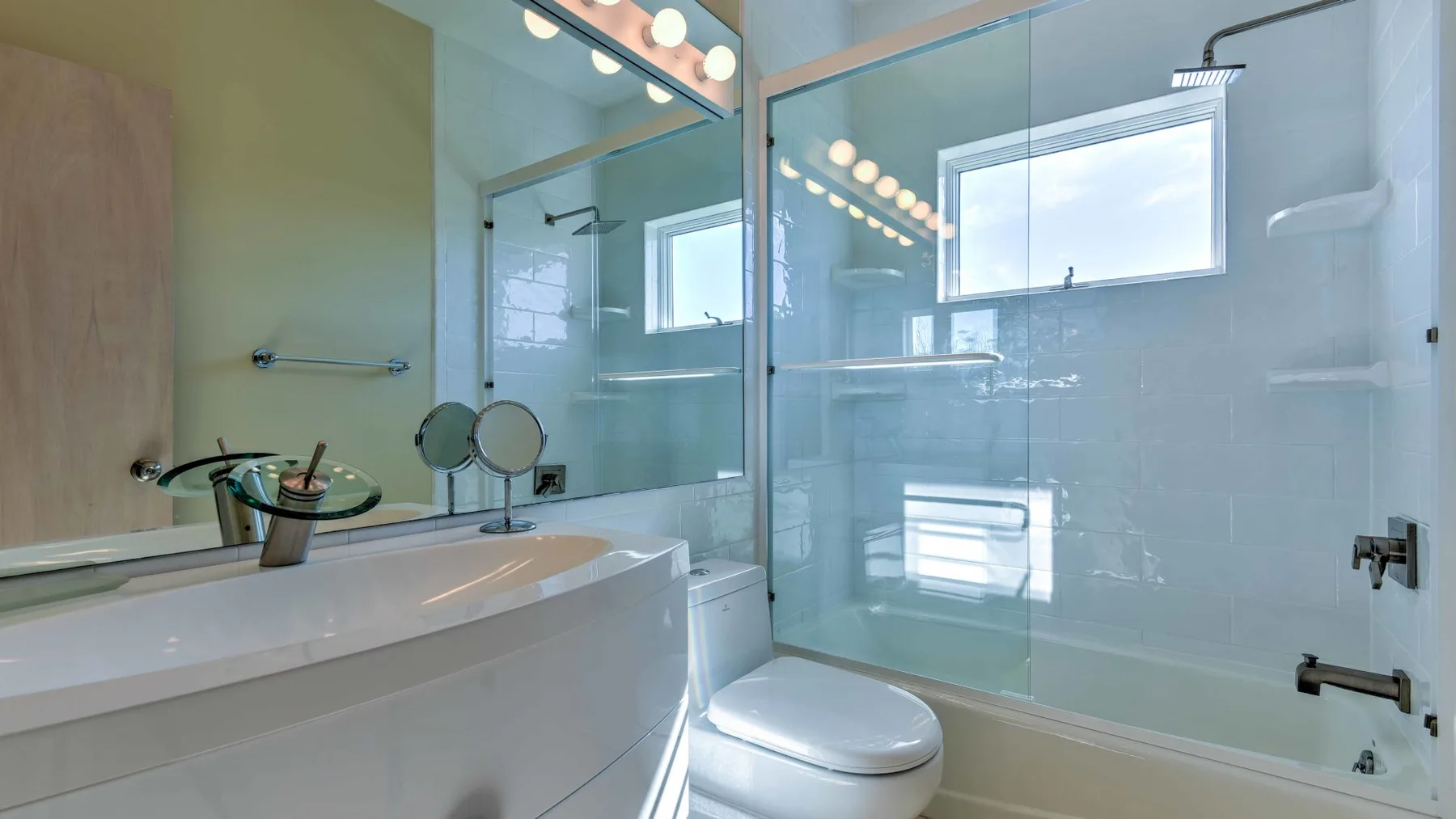 Un baño con bañera, mampara de vidrio y retrete.