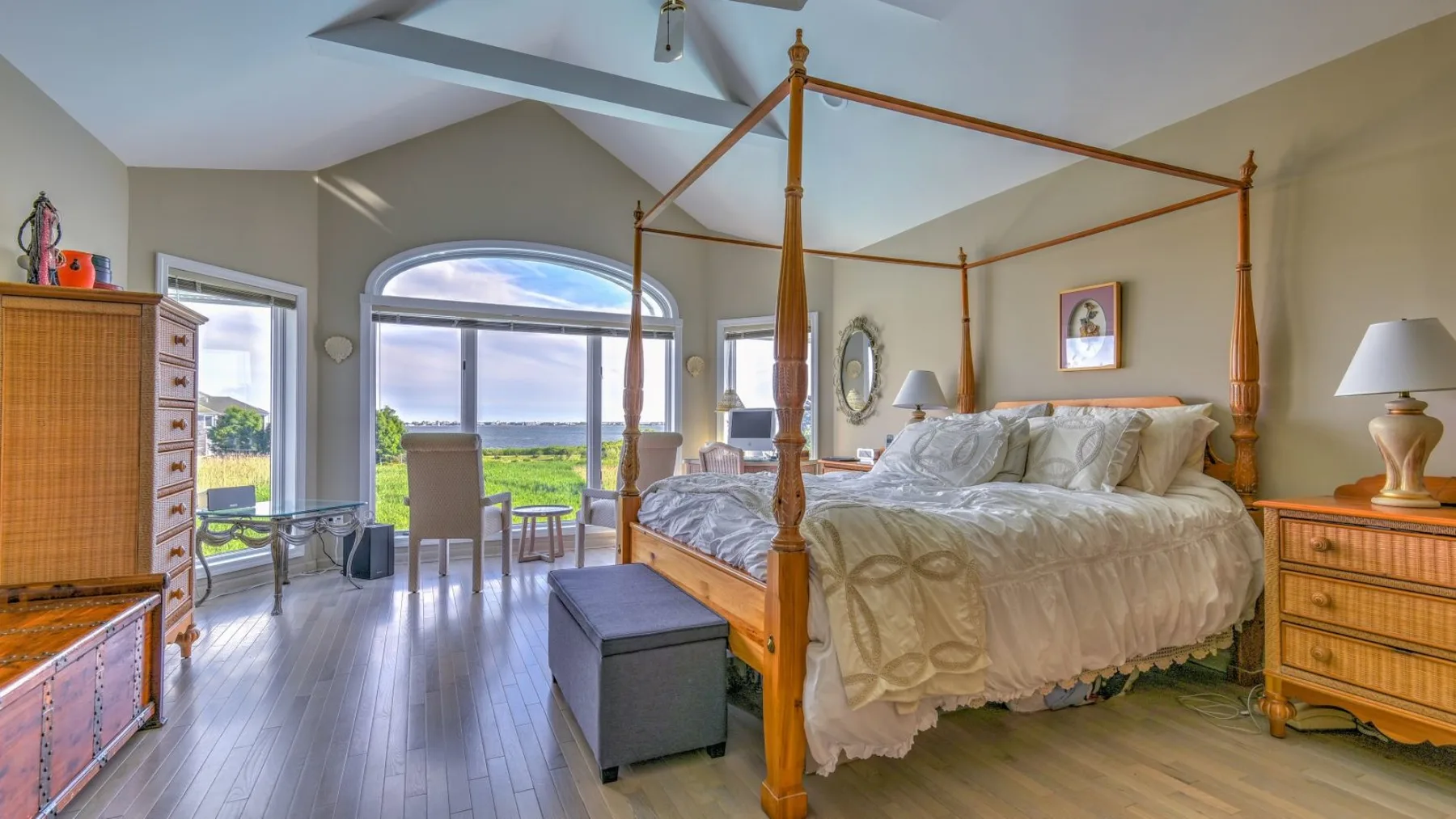 Un dormitorio luminoso con una cama con dosel y grandes ventanas con vistas a un lago.