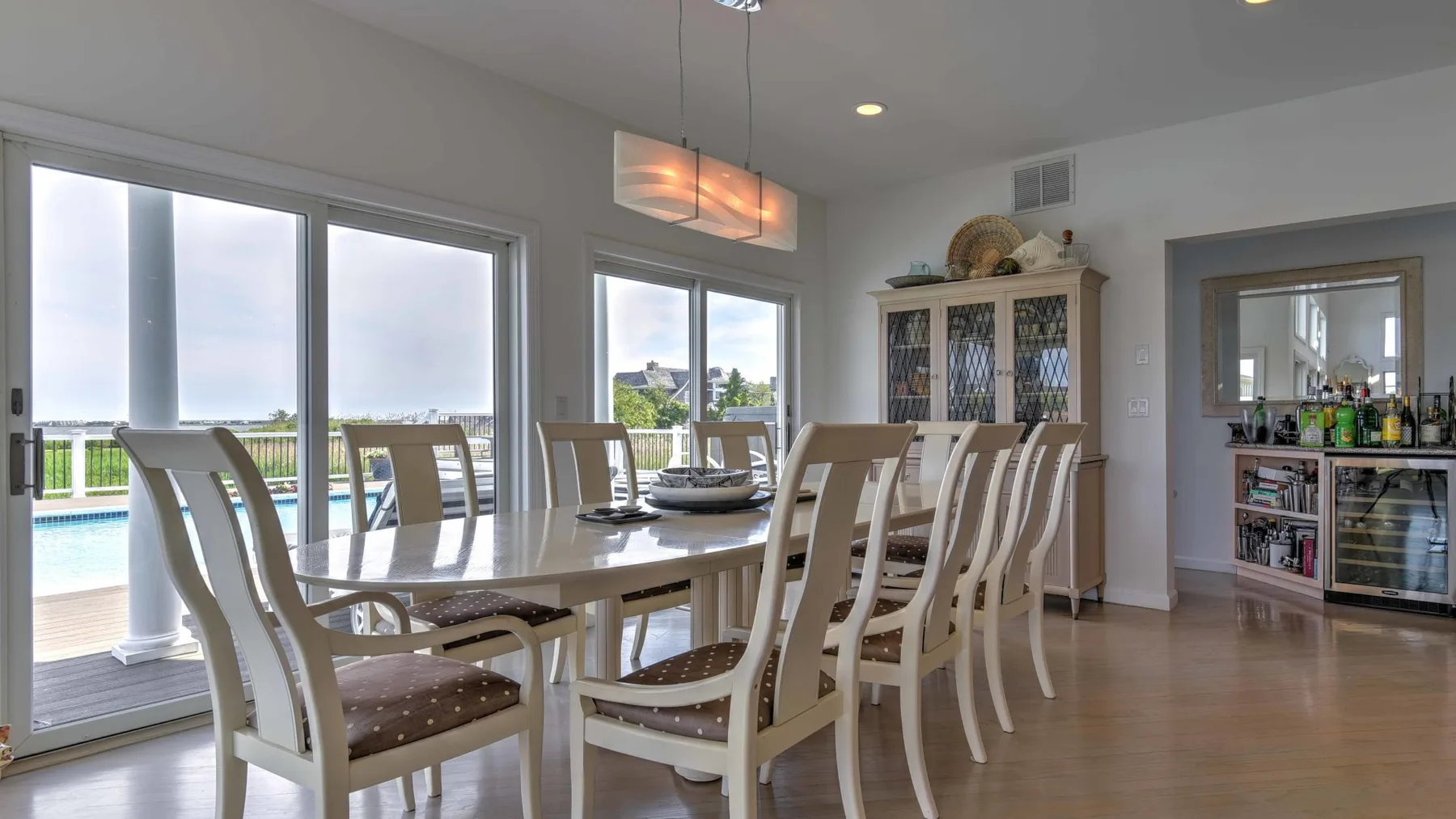 Un comedor luminoso con una mesa larga y grandes ventanas que dan a un patio.