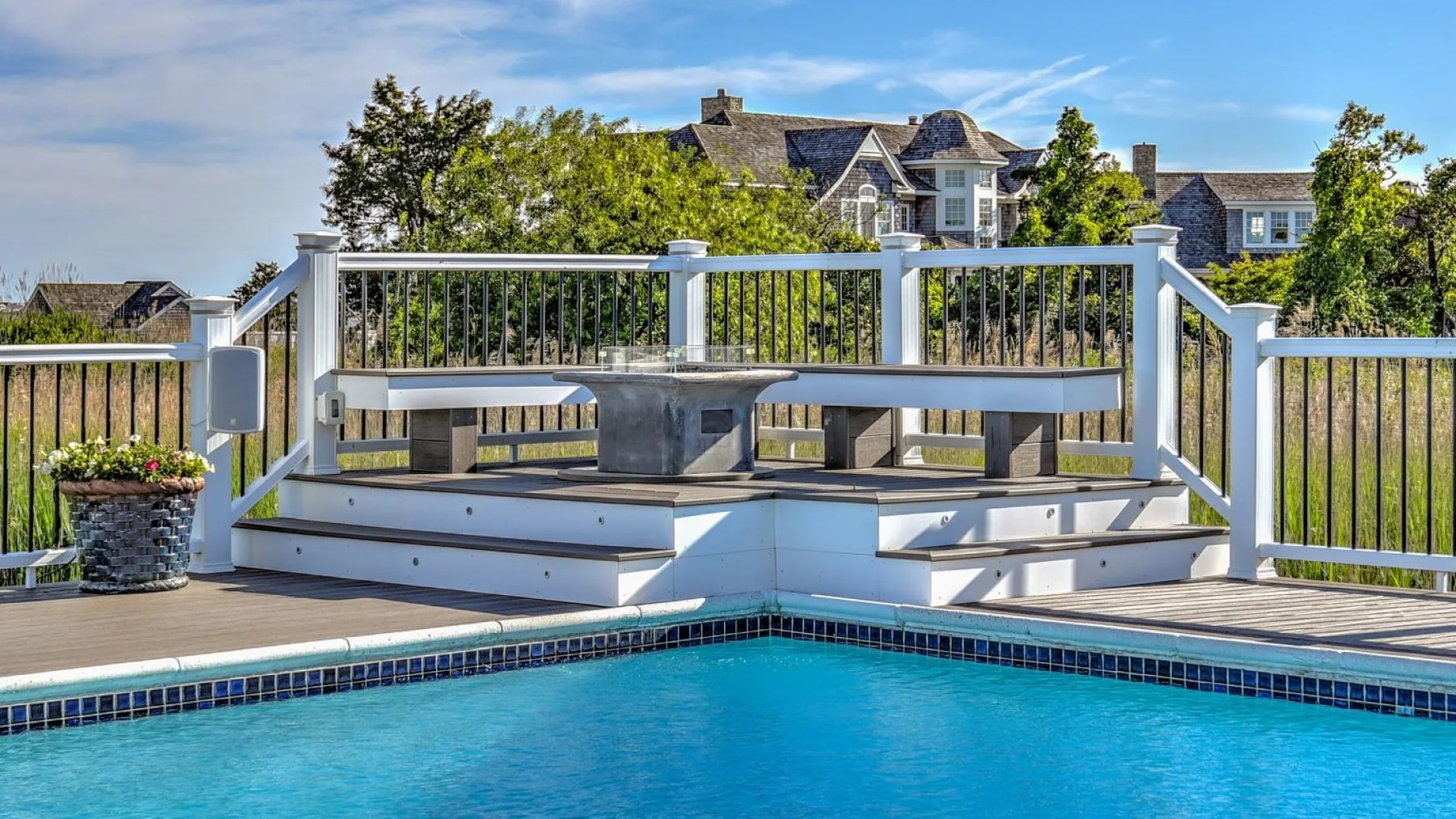 Una piscina al aire libre junto a una terraza elevada con asientos integrados.