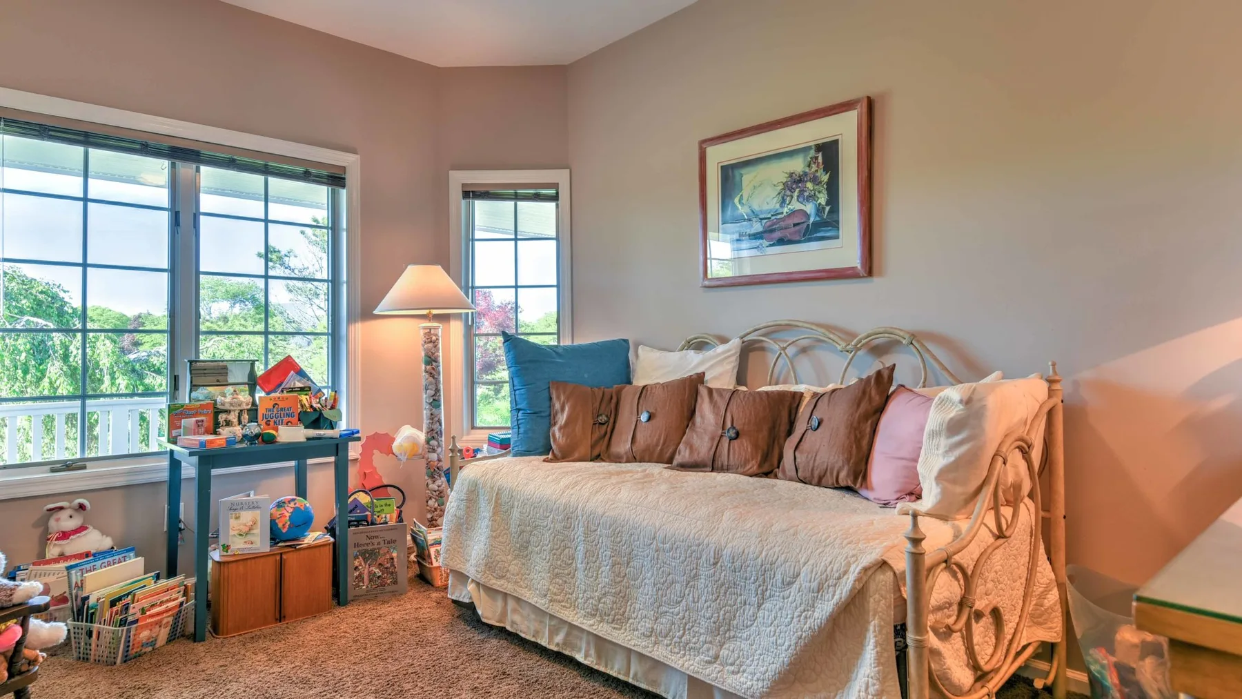 Un dormitorio con una cama, almohadas coloridas y ventanas grandes.