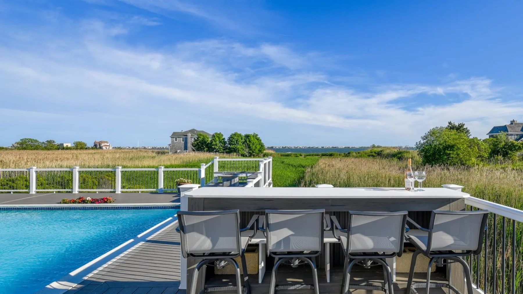 Una zona de comedor al aire libre junto a una piscina, con mesa y asientos.
