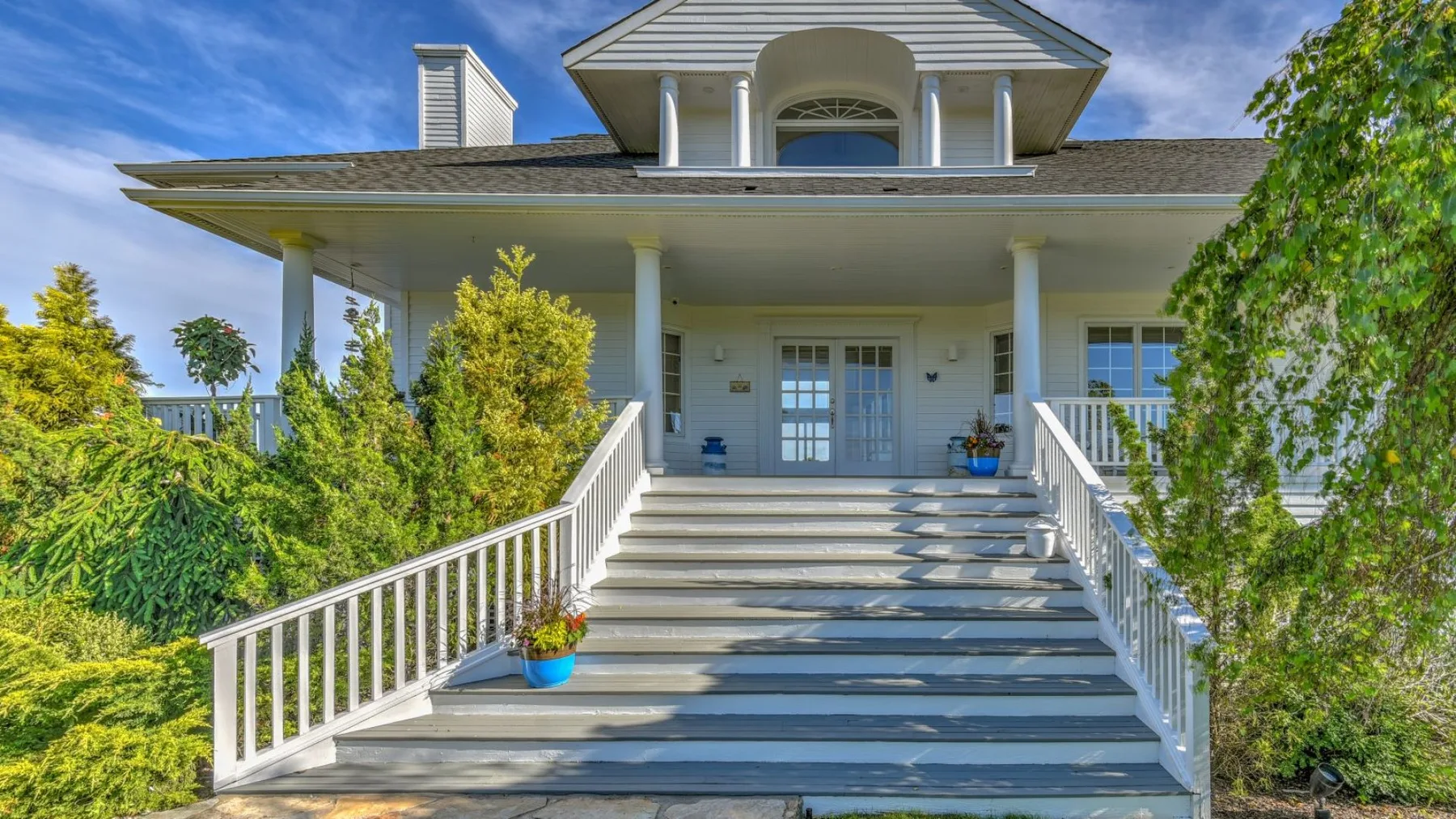 Una casa grande con una amplia escalera que conduce a un porche delantero cubierto.