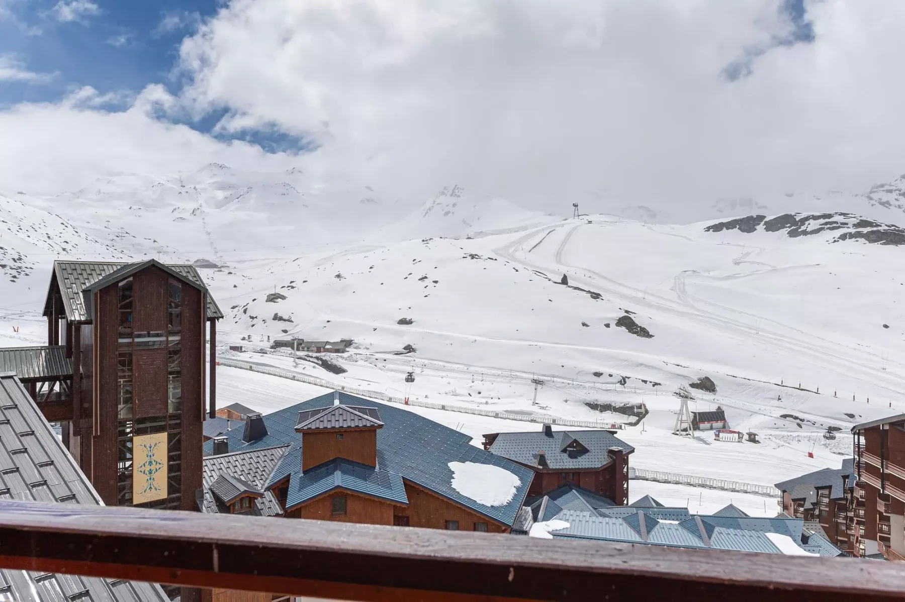 Laderas nevadas se alzan detrás de edificios con techos azules.