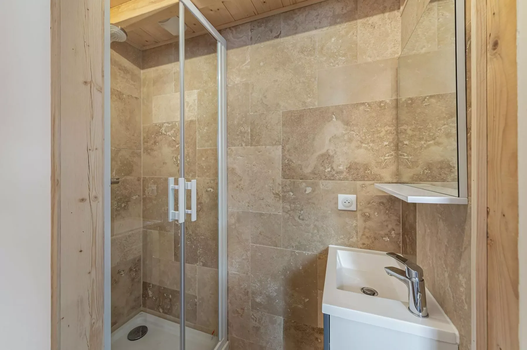 Un baño alicatado con una ducha de vidrio y un lavabo blanco.