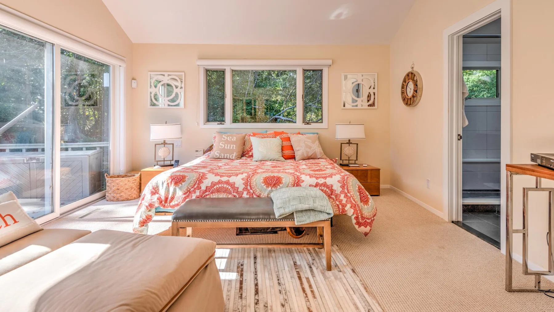 A bright bedroom with a bed centered beneath a wide window.