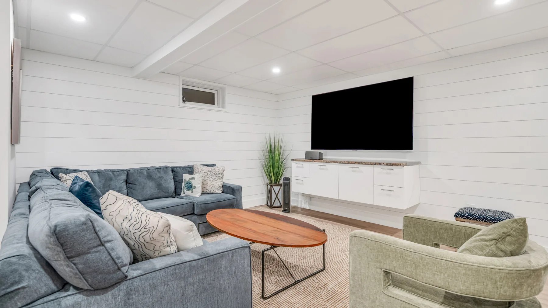 A living room with seating around a wooden coffee table and a wall-mounted television.