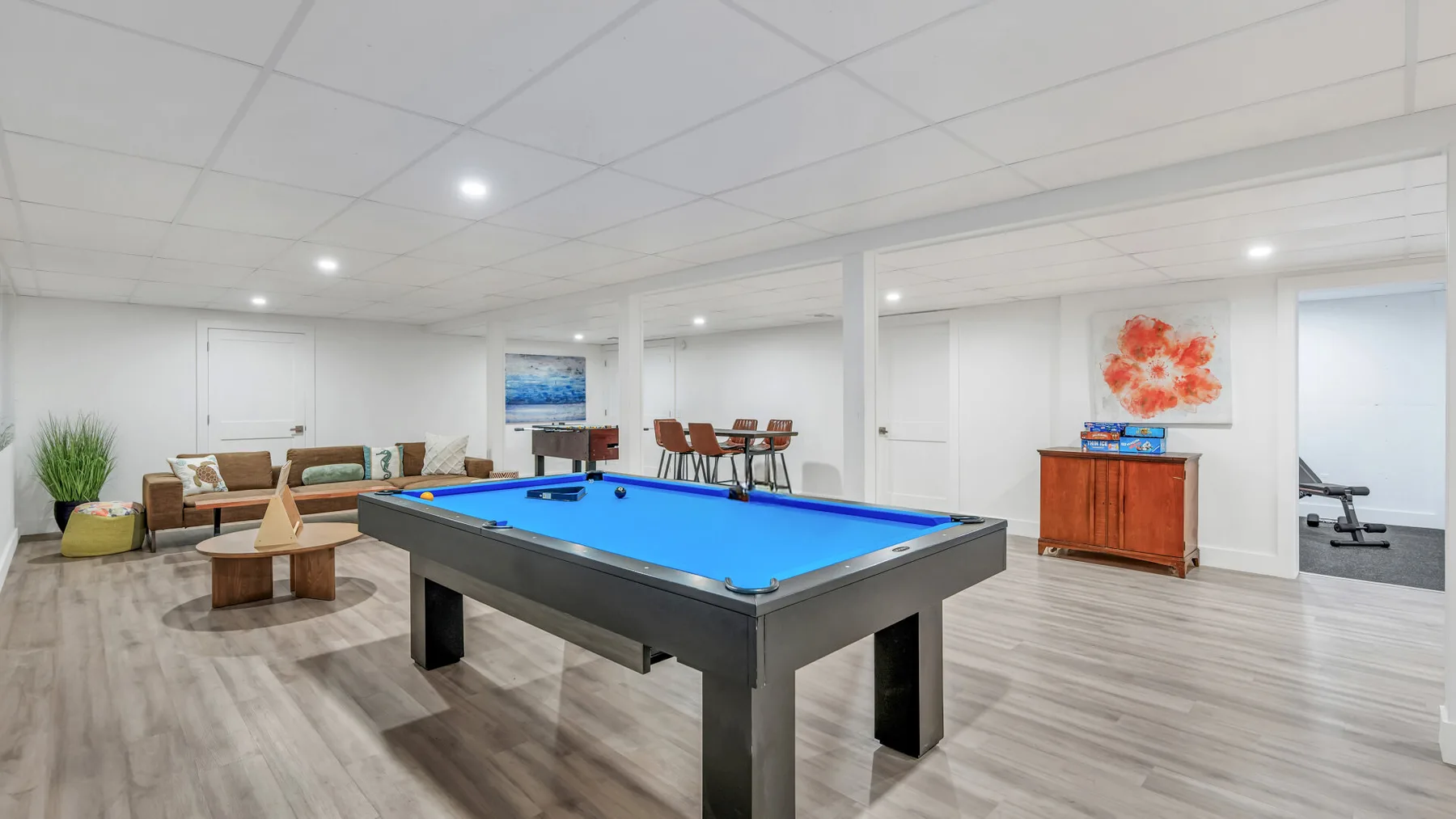 A recreation room with a blue-felt pool table and seating.