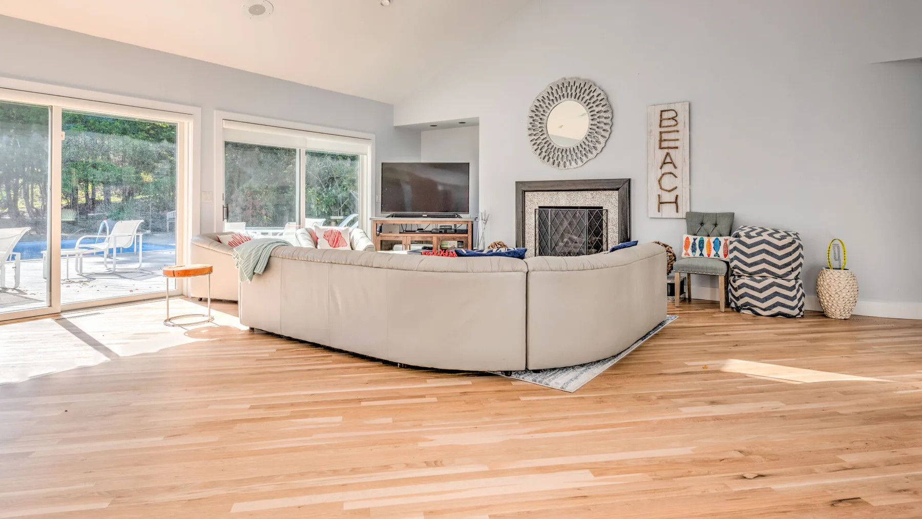 A bright living room with a large seating area facing a fireplace and television.